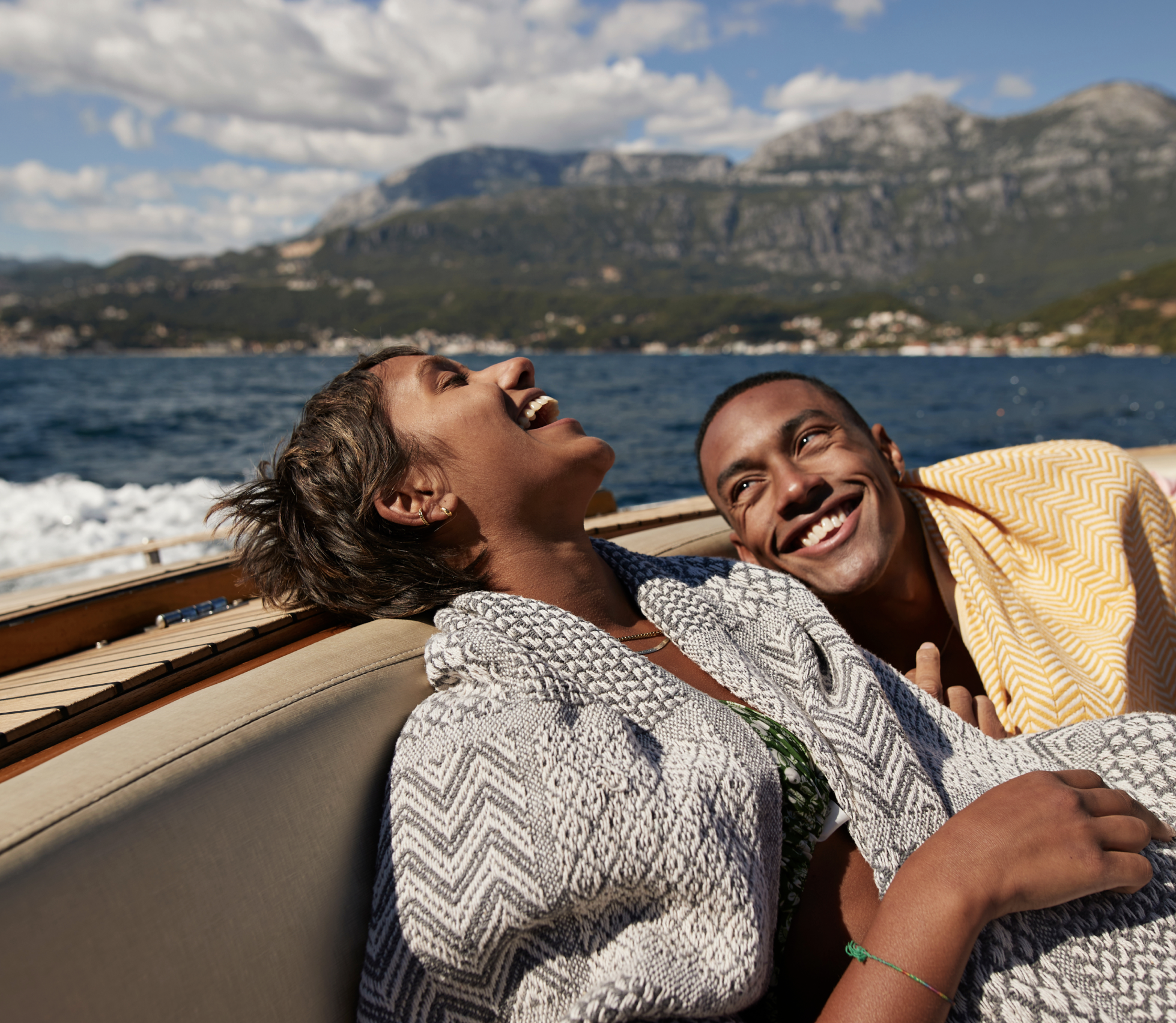Couple laughing on boat trip with vacation mountain view in the back.