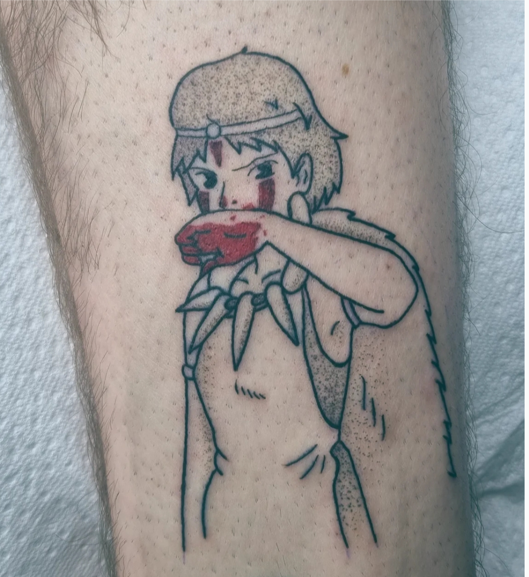 Tattoo of a cartoon girl with short hair and a headband, covering her face with her hand, which is smeared with red ink or paint. The girl has a serious expression and is drawn in a simple, bold outline style, with some color accents.
