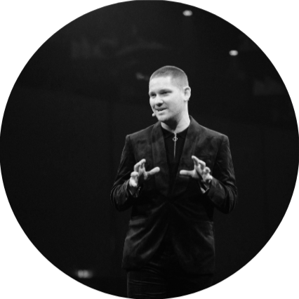 A man in a suit making a gesture with his hands on a stage.