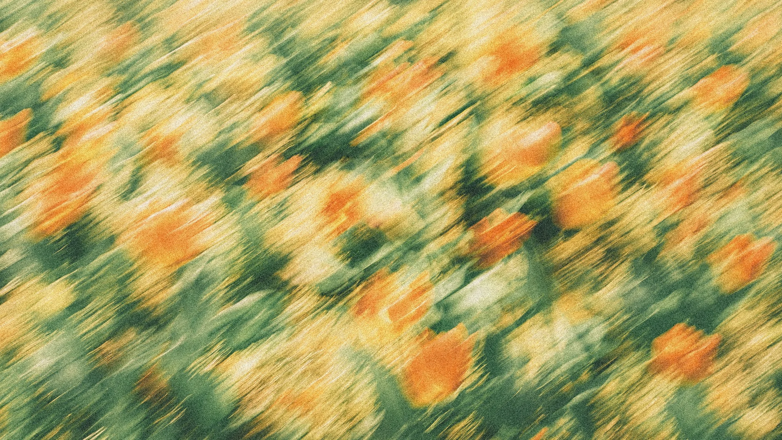 Blurry, abstract close-up of orange and yellow flowers with green leaves.