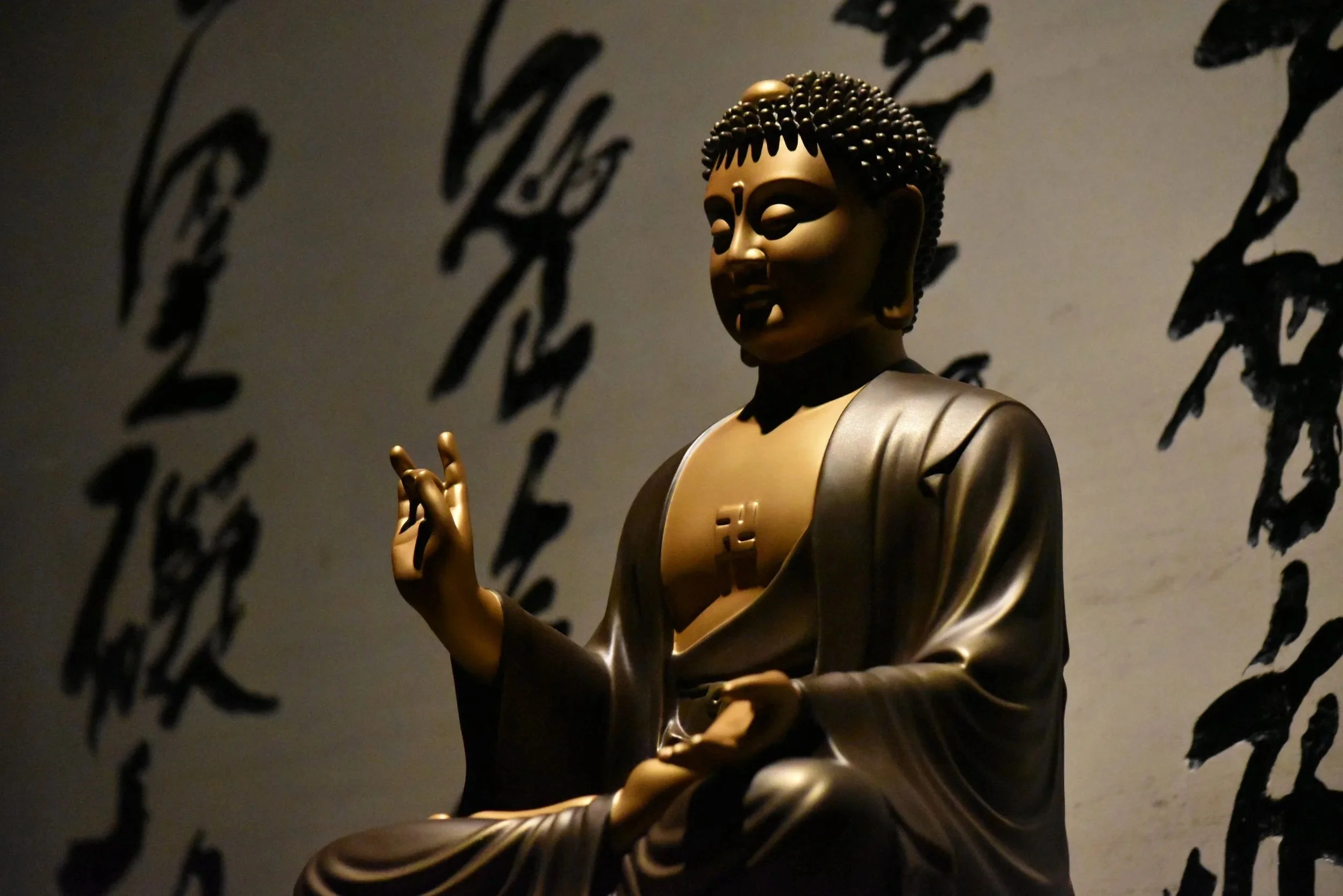 Scultura di Buddha dorato con sfondo nero e scritte in caratteri asiatici