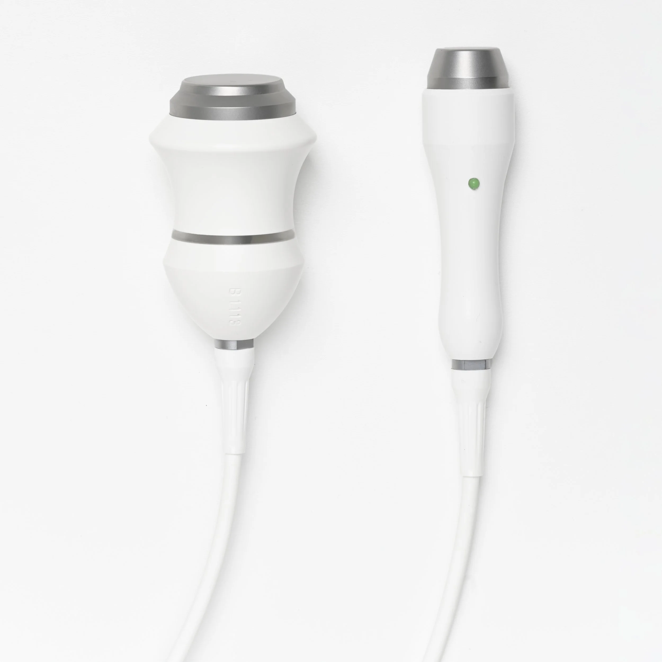 Two white electronic devices with metallic accents, connected to white cables against a plain white background.