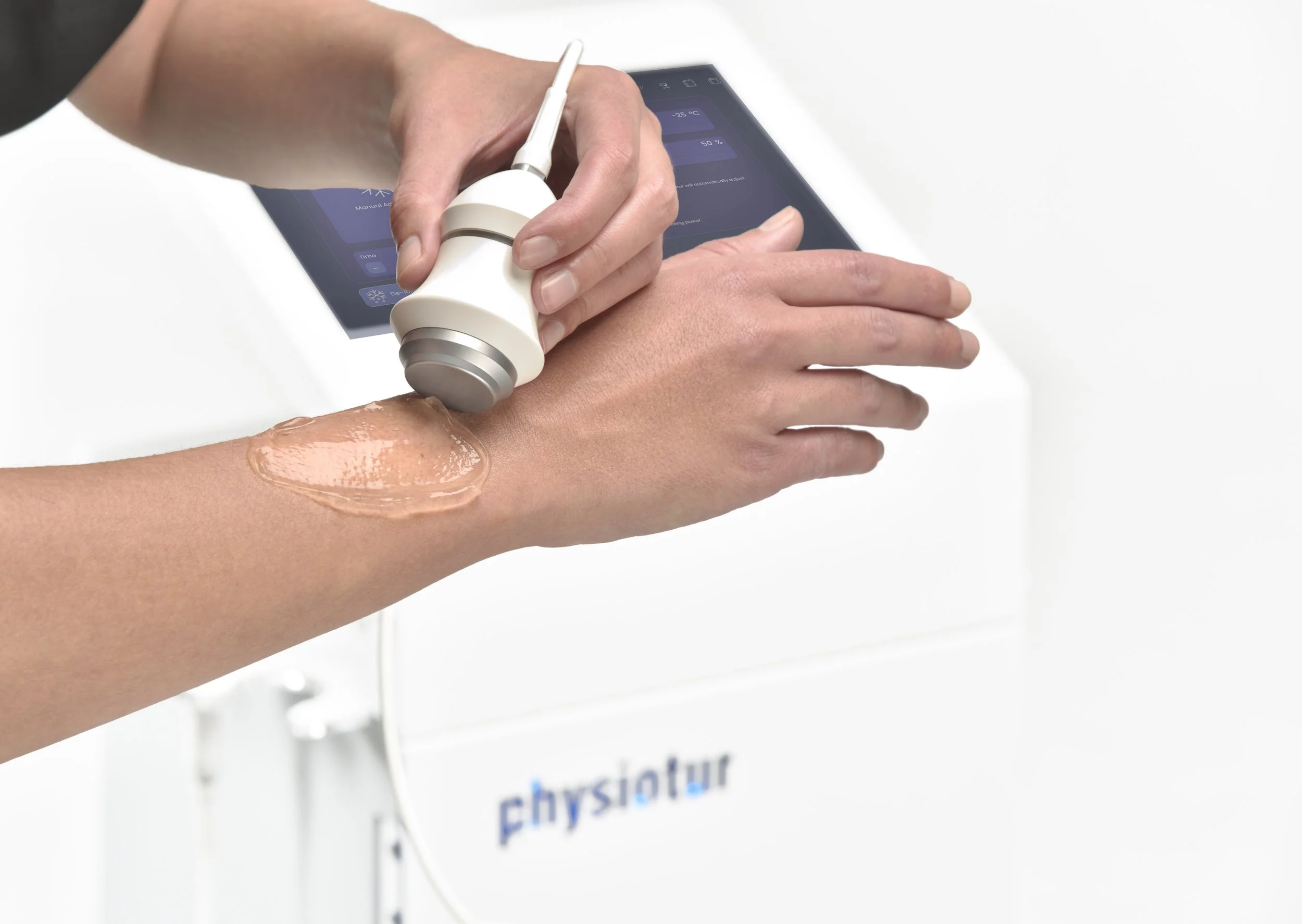 A person using a handheld ultrasonic device on another person's forearm, with gel applied for treatment, near a digital screen showing health data.