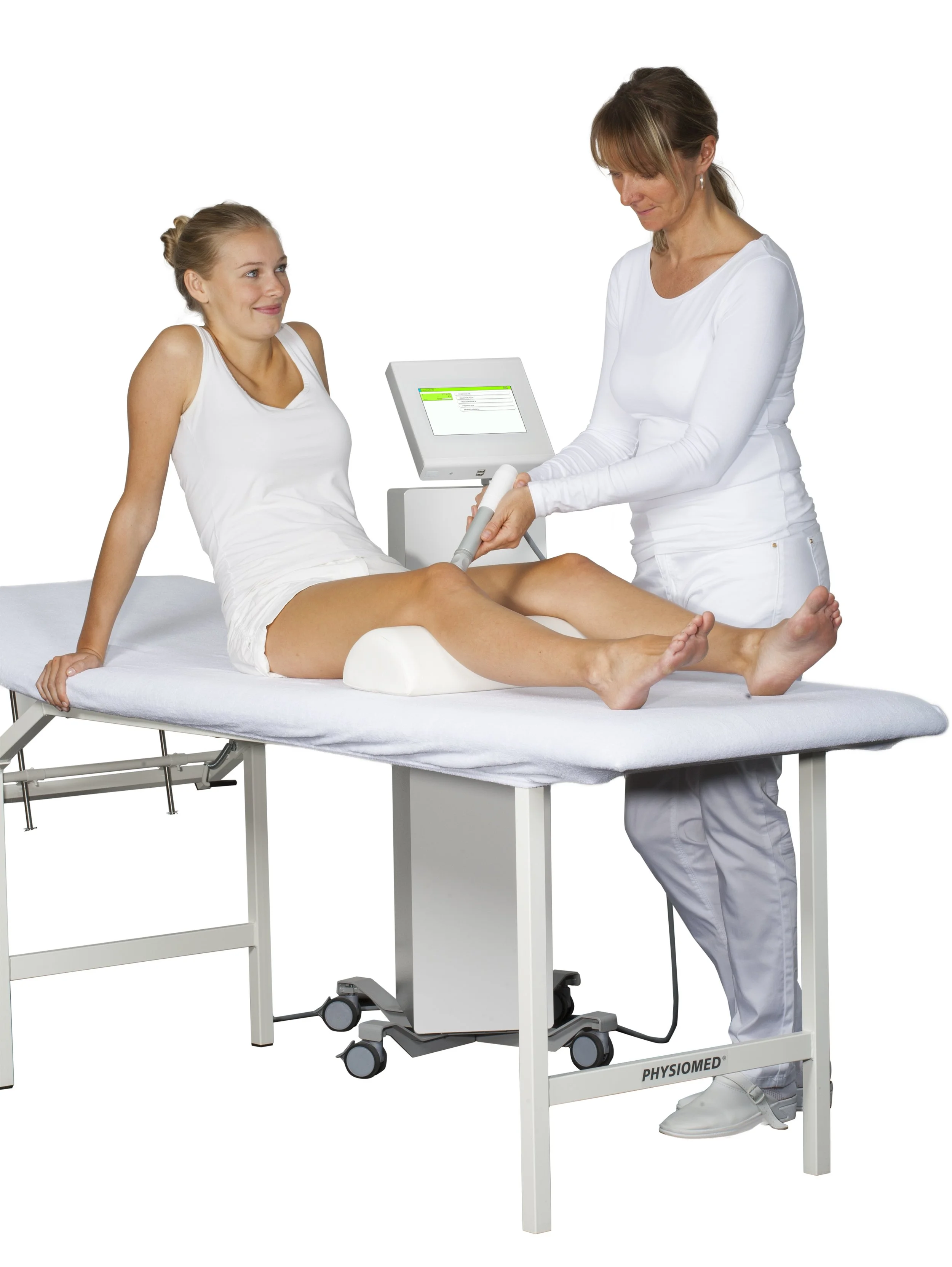 A woman sitting on a medical examination table receiving ultrasound treatment from a healthcare professional. The professional is holding an ultrasound probe, and a monitor displays the ultrasound readings.
