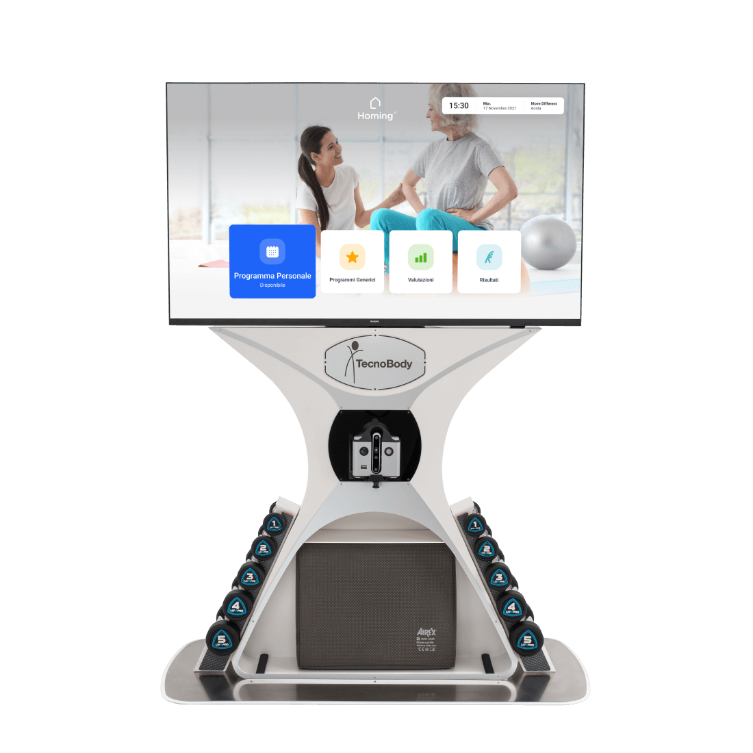 A medical or rehabilitation device with a large touchscreen display showing a wellness or fitness program, words in Italian, and a background with a woman and a healthcare provider or trainer in a bright room.
