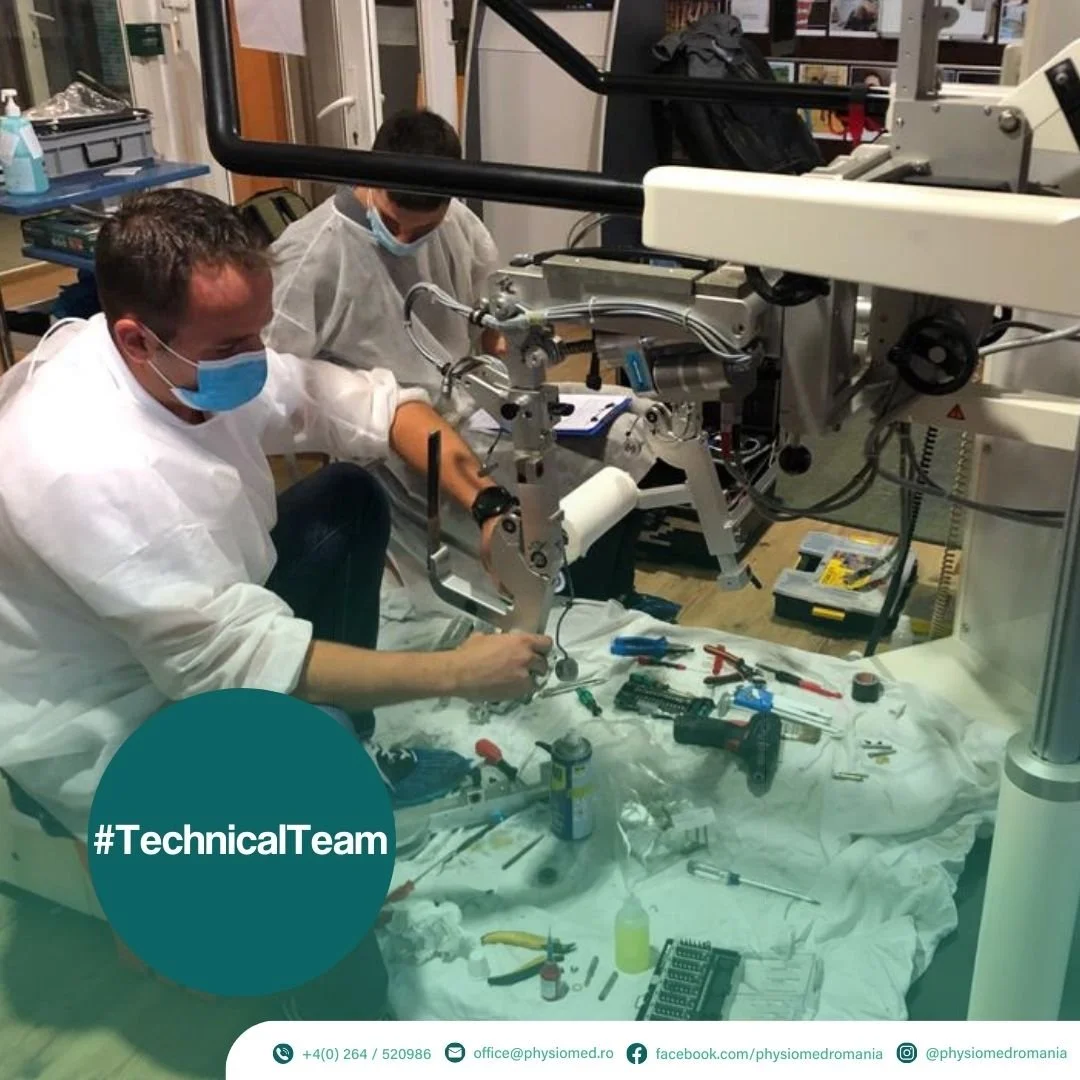Two scientists working on a mechanical device in a laboratory, wearing masks and protective gear, with tools and equipment on the table.