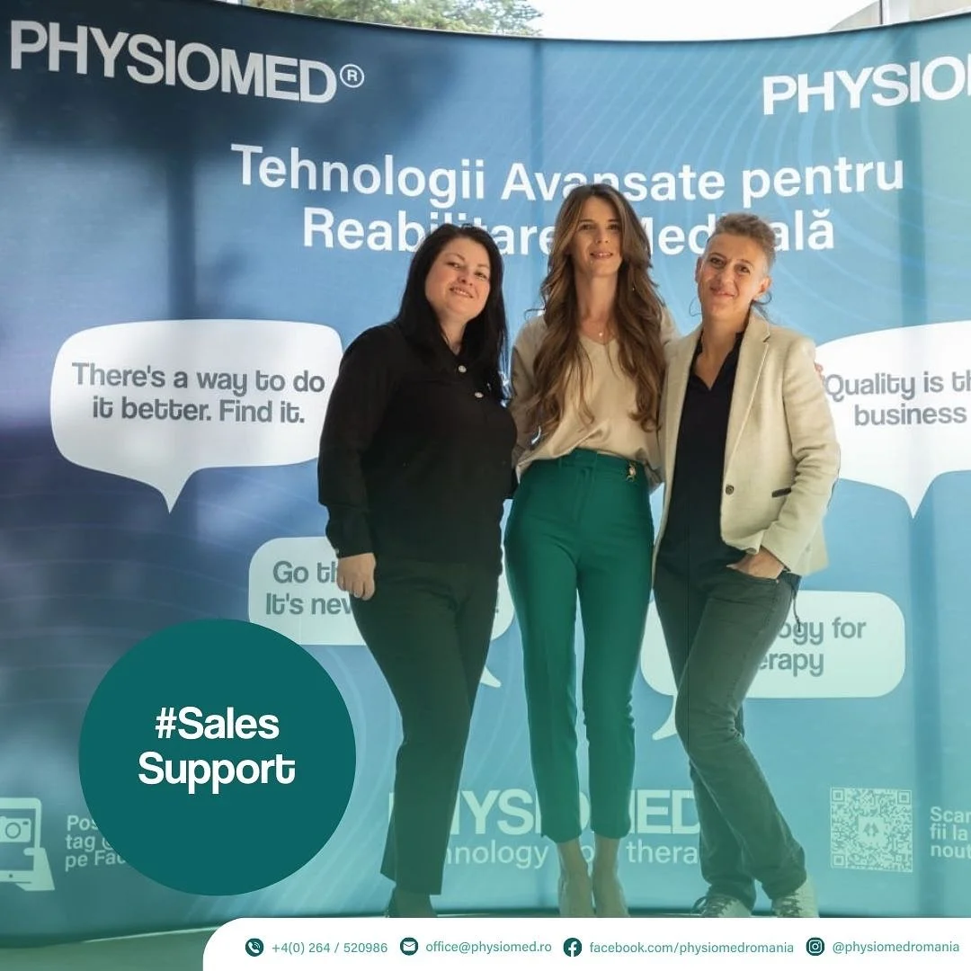 Three women standing in front of a blue banner at a medical technology event. The banner displays the texts 'PHYSIOMED,' 'Tehnologii Avansate pentru Reabilitare Medicală,' and speech bubbles with messages about improving healthcare and therapy. The women are dressed professionally, smiling, and posing for the photo.