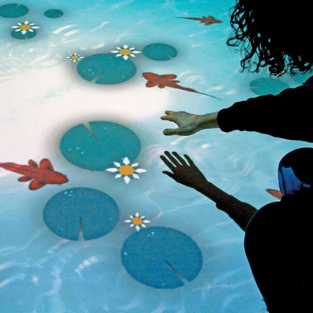 A person with curly hair and a person with darker skin reaching towards a digital screen with floating aquatic plants, flowers, and fish.