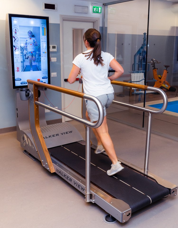 A woman using a treadmill with a virtual reality system indoors, with gym equipment visible in the background.