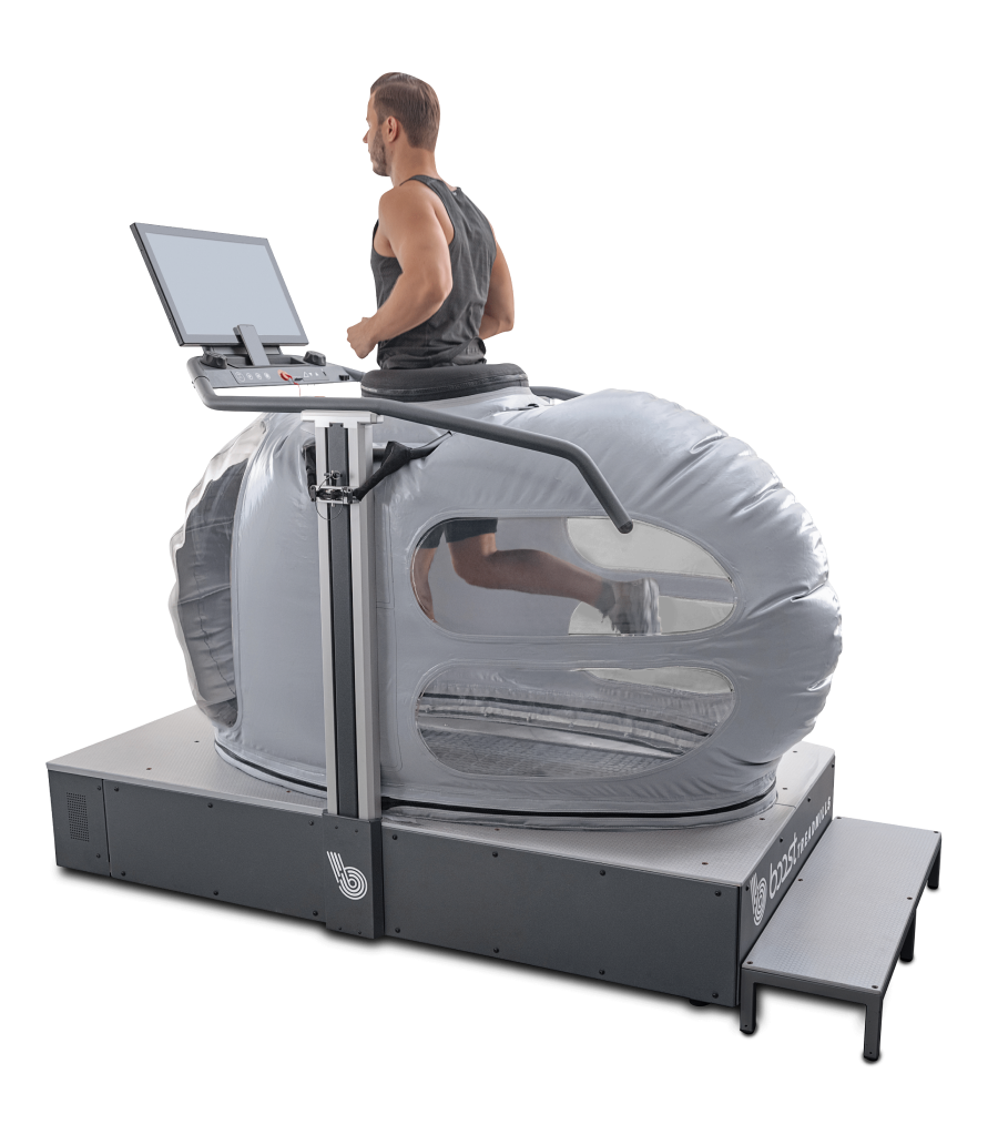 A person running on a treadmill enclosed inside a transparent, pod-like structure with a control screen and monitoring equipment.