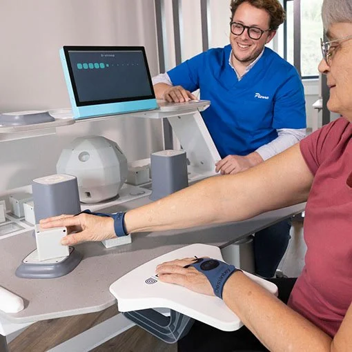 A healthcare professional conducts a blood pressure test on an elderly woman using a digital cuff monitor, while smiling at her, in a clinical setting.