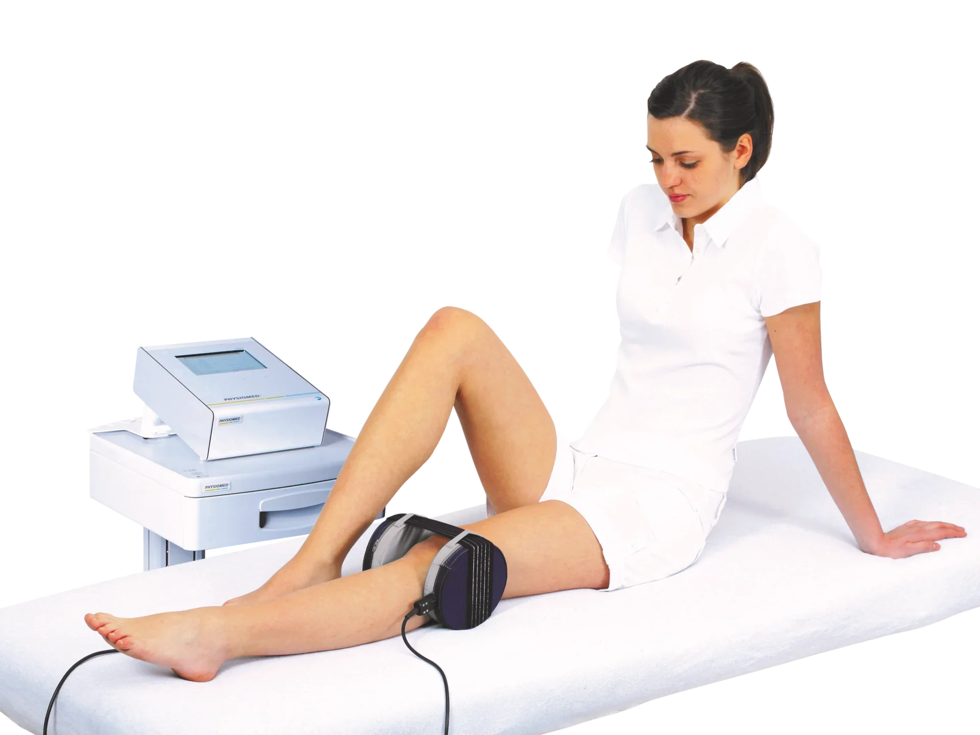 A woman sitting on a medical examination table with her legs bent, using a blood pressure cuff on her thigh while a healthcare worker monitors a medical device.