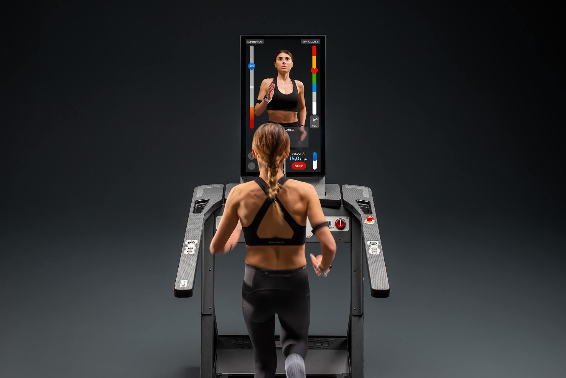 A woman running on a treadmill with a screening monitor displaying her workout data and a virtual coach in front of her.