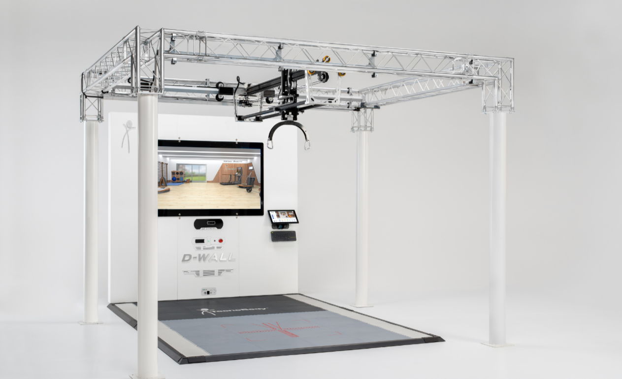 A robotic rehabilitation device with a metal frame, a large touch-screen display, and a padded walking surface, used for physical therapy and gait training.