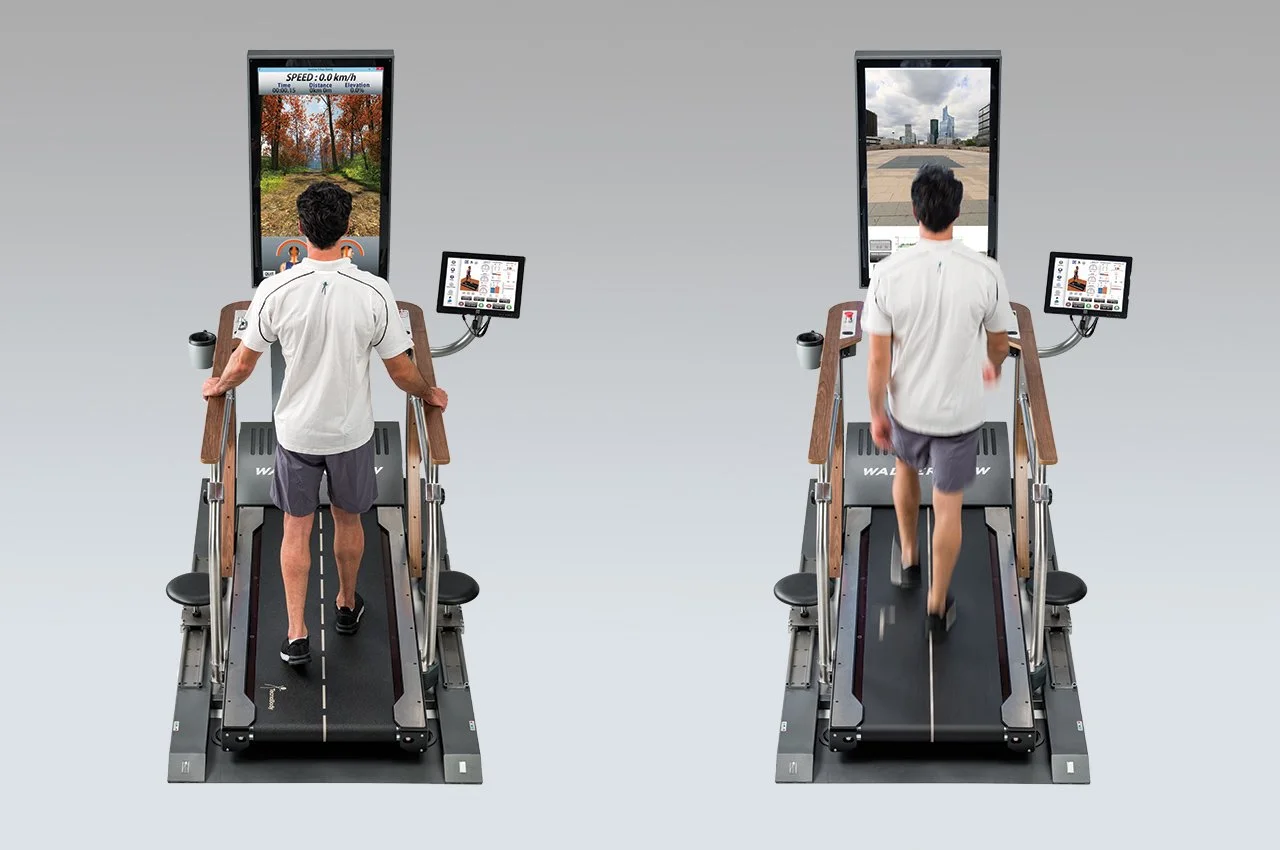 Two men walk on a treadmill with screens in front of them, one showing a forest scene and the other showing an urban cityscape, with accompanying control panels.