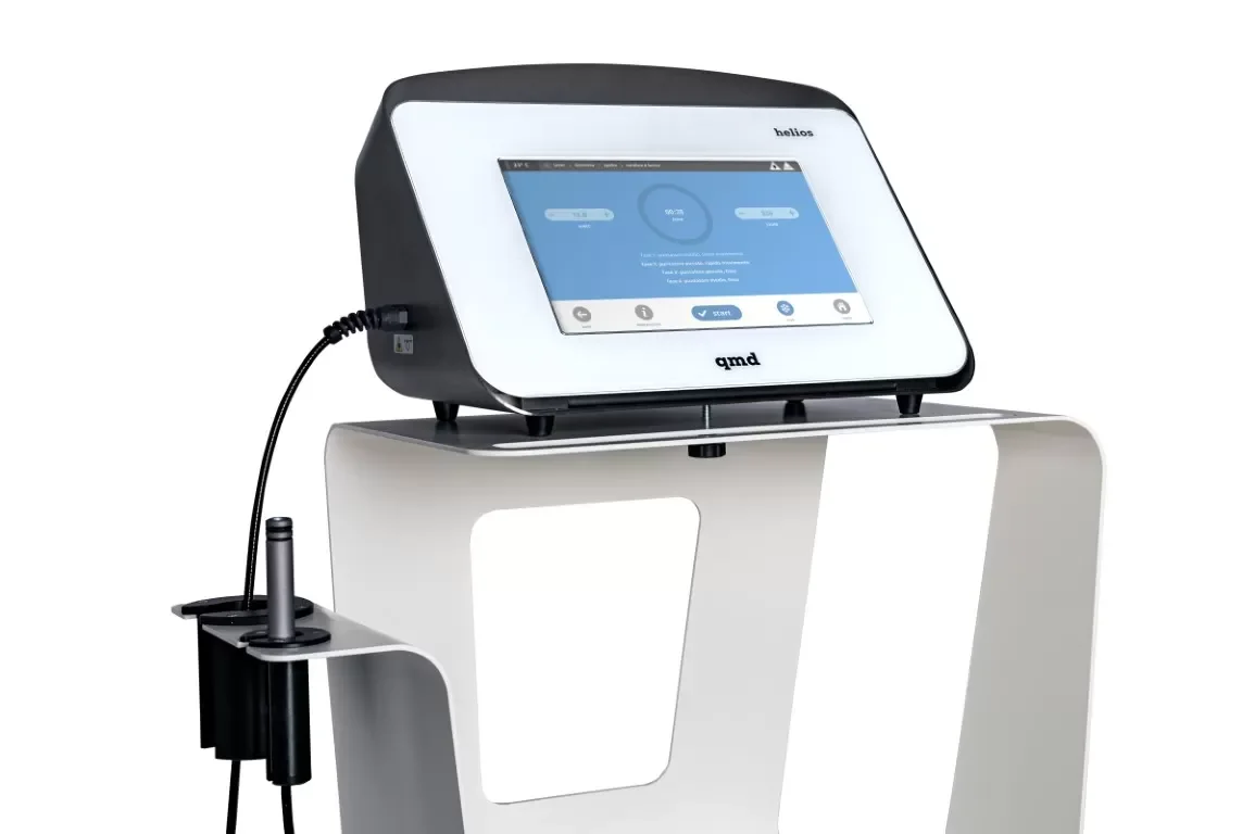 Medical device with touchscreen interface on a white table, connected by a cable to a probe or applicator on the side