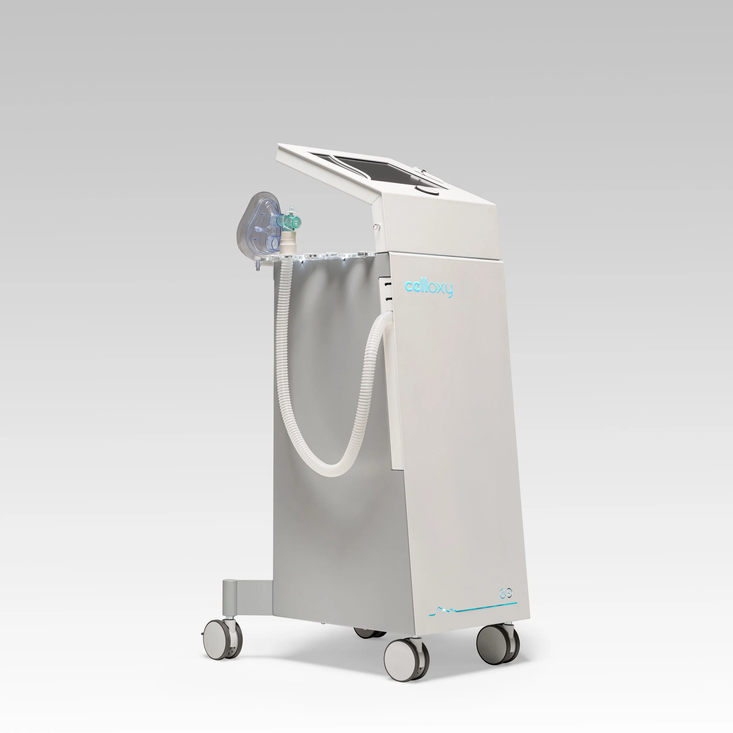 Medical device on wheels with a transparent breathing mask attached to a tube, and a touchscreen interface on top, labeled 'celloxy'.