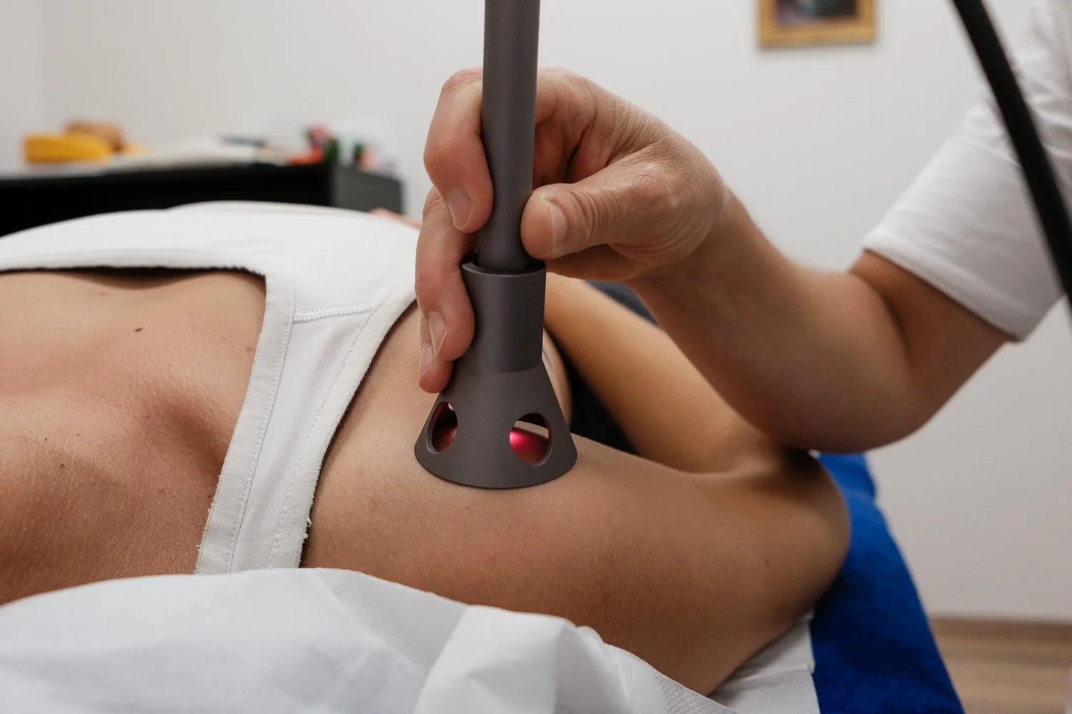 A healthcare professional performing ultrasound treatment on a patient's shoulder using a handheld ultrasound device.