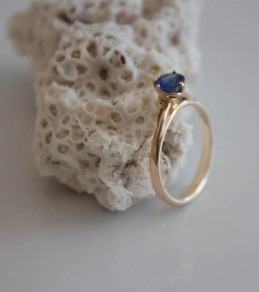 Bague en or avec une pierre bleue, posée sur une pièce de corail blanc.