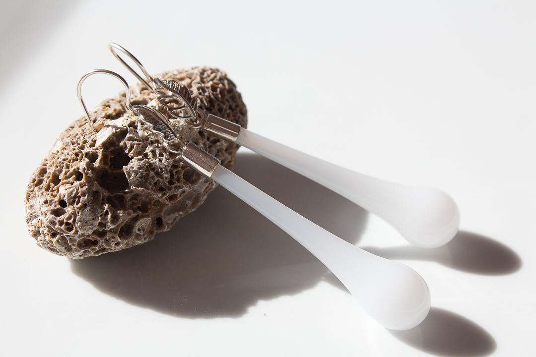 Deux éponges naturelles pour le nettoyage avec deux spatules en plastique blanc posées dessus, sur un fond blanc.