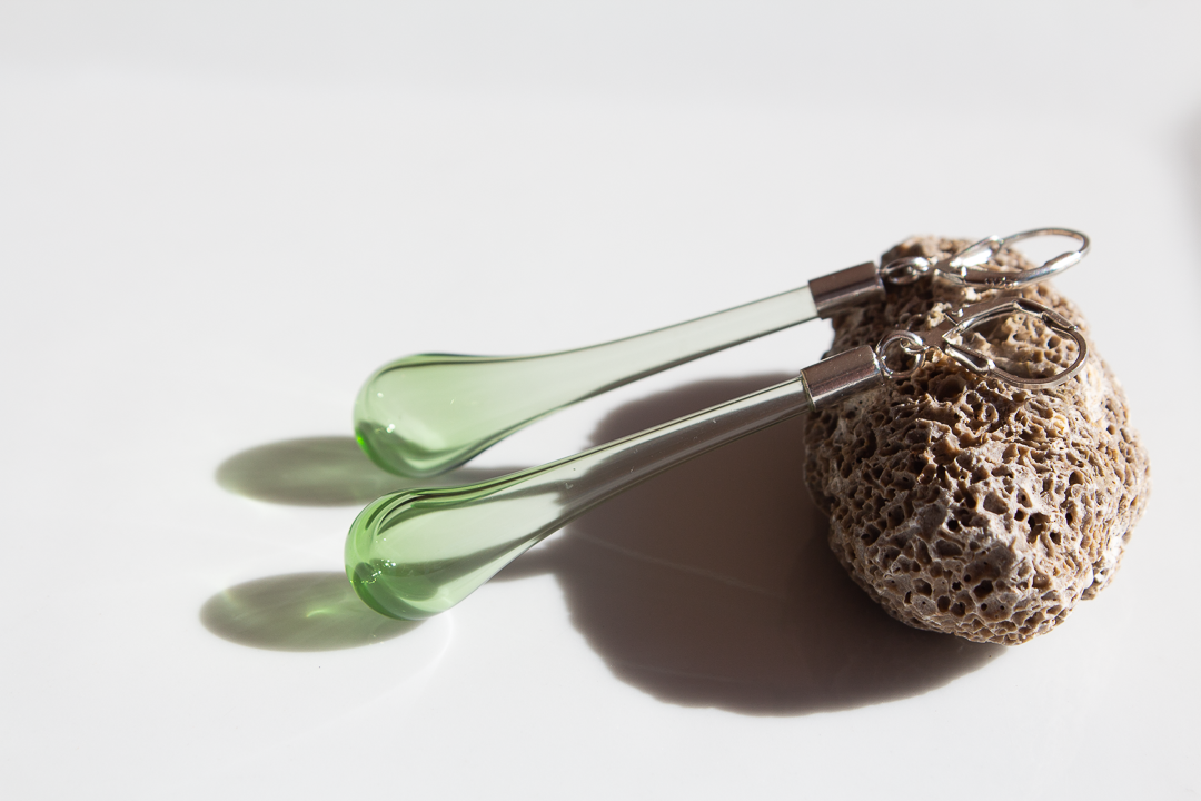 Boucles d'oreilles en verre vert avec éponges naturelles, sur un fond blanc.