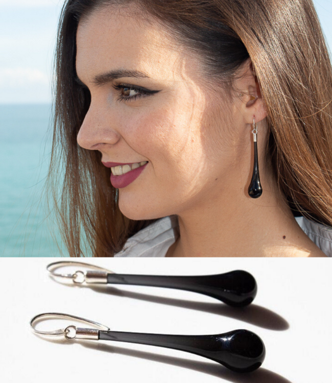 Une femme souriante avec une boucle d'oreille en forme de goutte noire et une image de deux attachés de boucle d'oreille en forme de goutte noir.