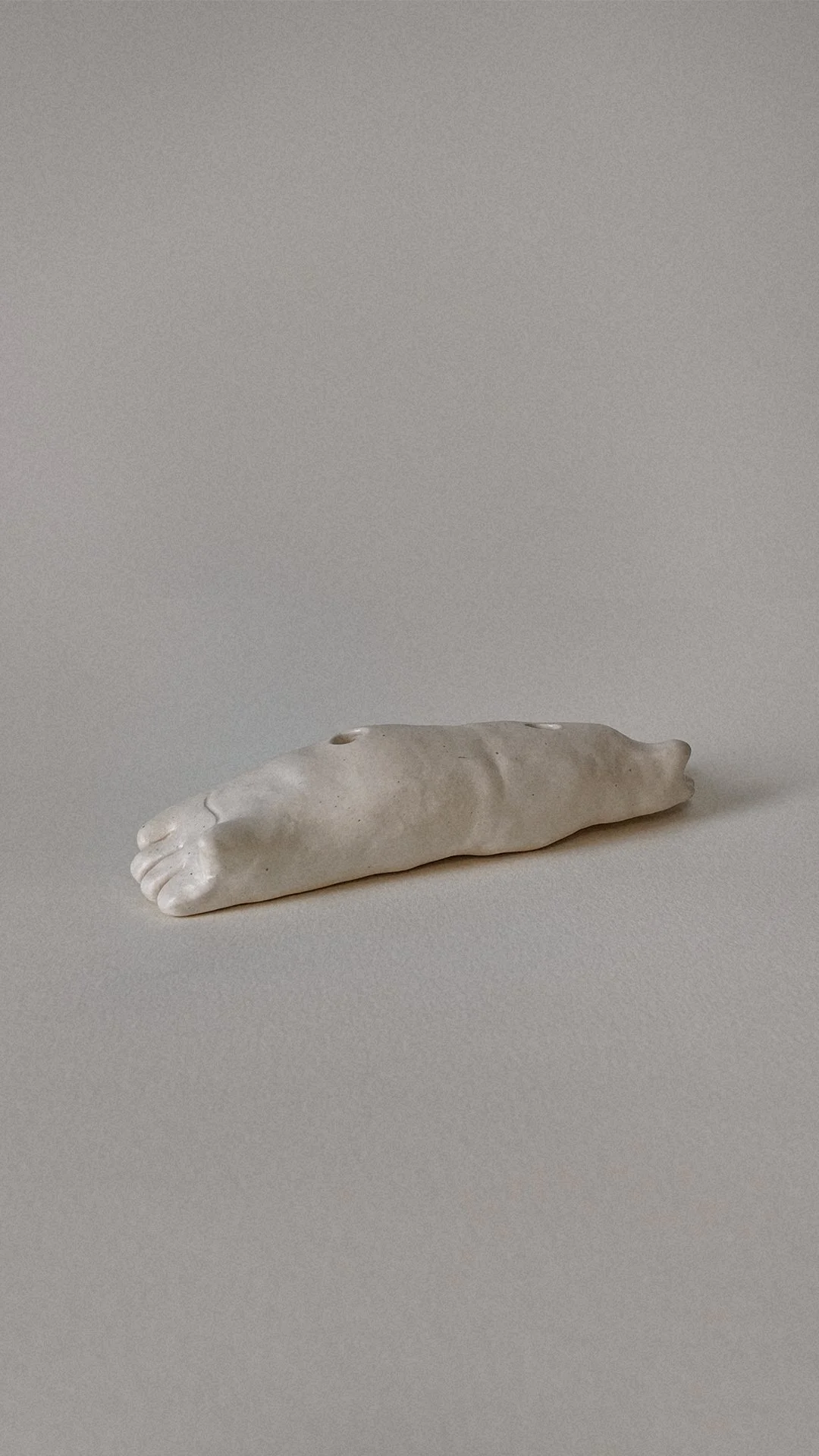 A small sculpture of a foot carved from white or light-colored stone.