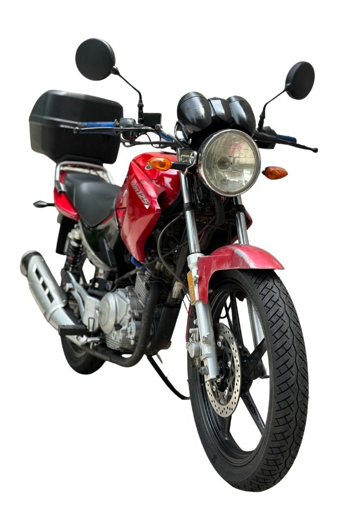 Red motorcycle with black storage box on back, front view showing headlight and front tire.