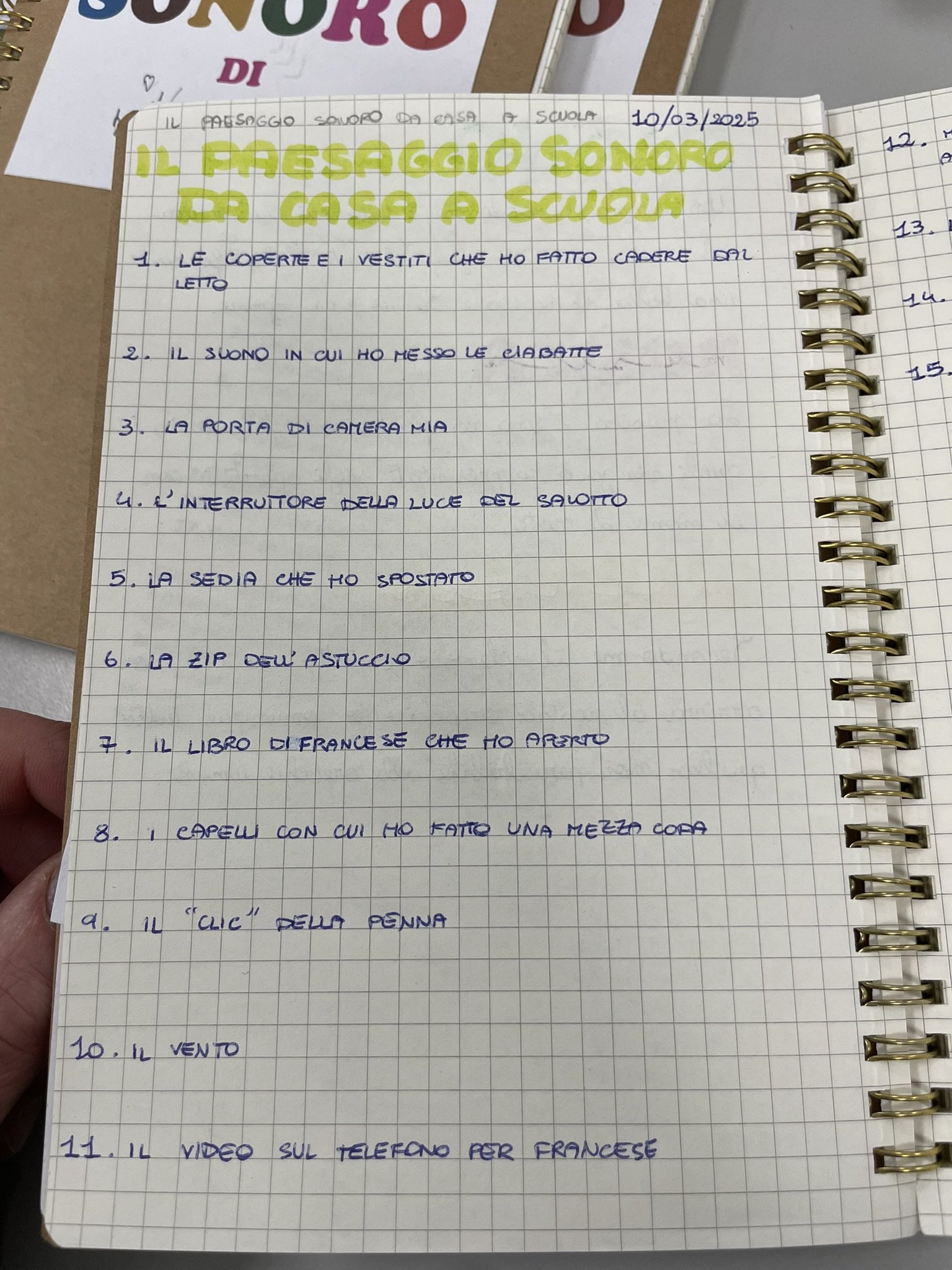Nota scritta a mano su quaderno a quadretti con una lista di cose legate ai ricordi di scuola e casa, tra cui copertine, suoni, camera, interruttore, sedia, zip, libro, capelli, clic, vento e video.