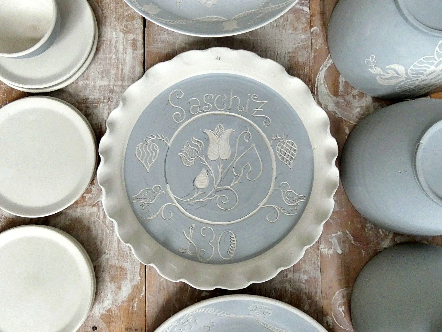 Piatti decorativi in ceramica con dettagli incisi, uno con il nome Sascha e il numero 30.
