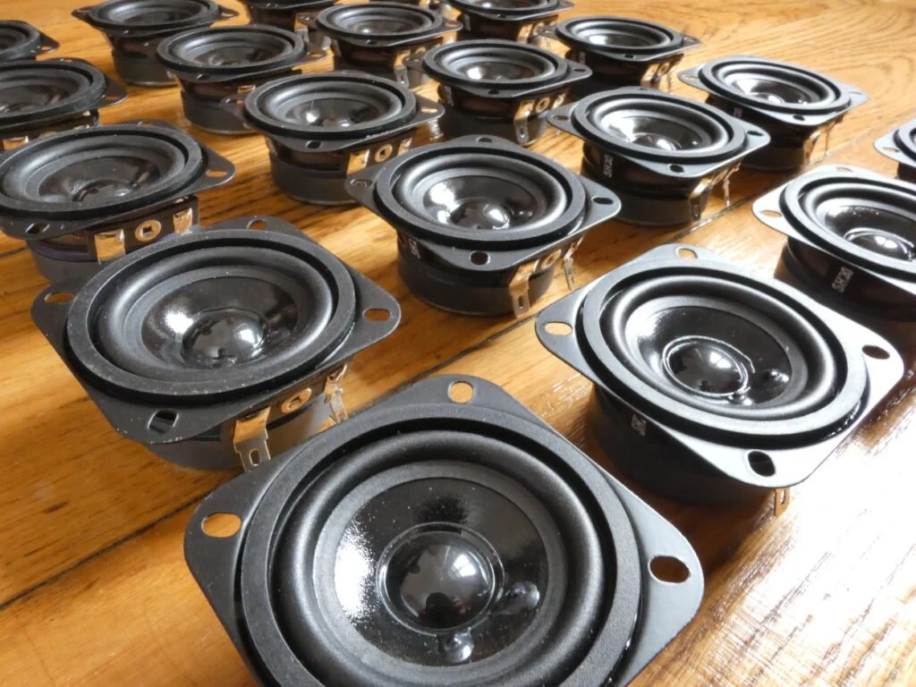 Alcuni altoparlanti da auto con componenti montati su una superficie in legno.
