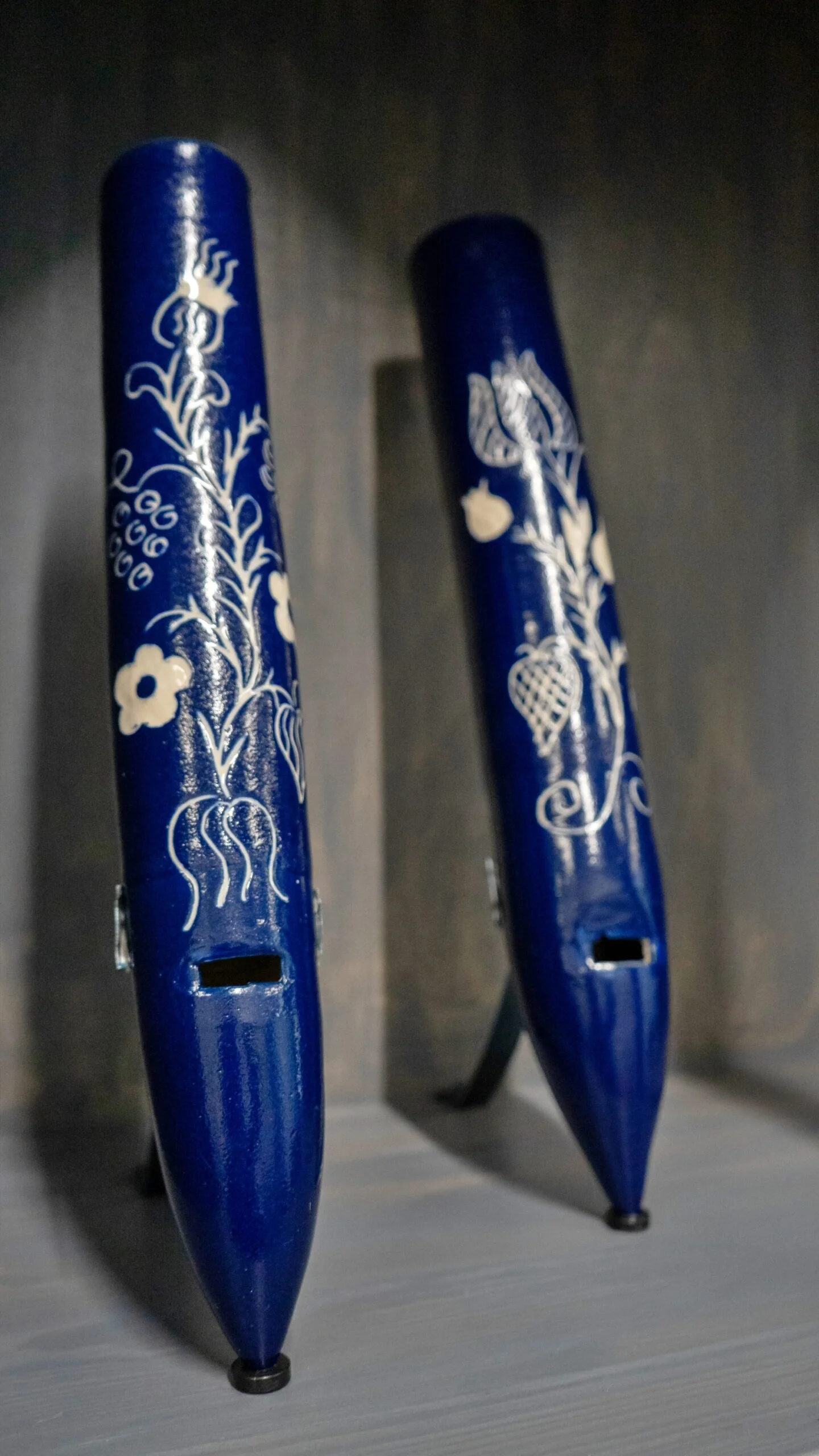 Due grandi zampilli azzurri con decorazioni floreali bianche, collocate su un supporto. Sembra un'opera d'arte o un'installazione decorativa.