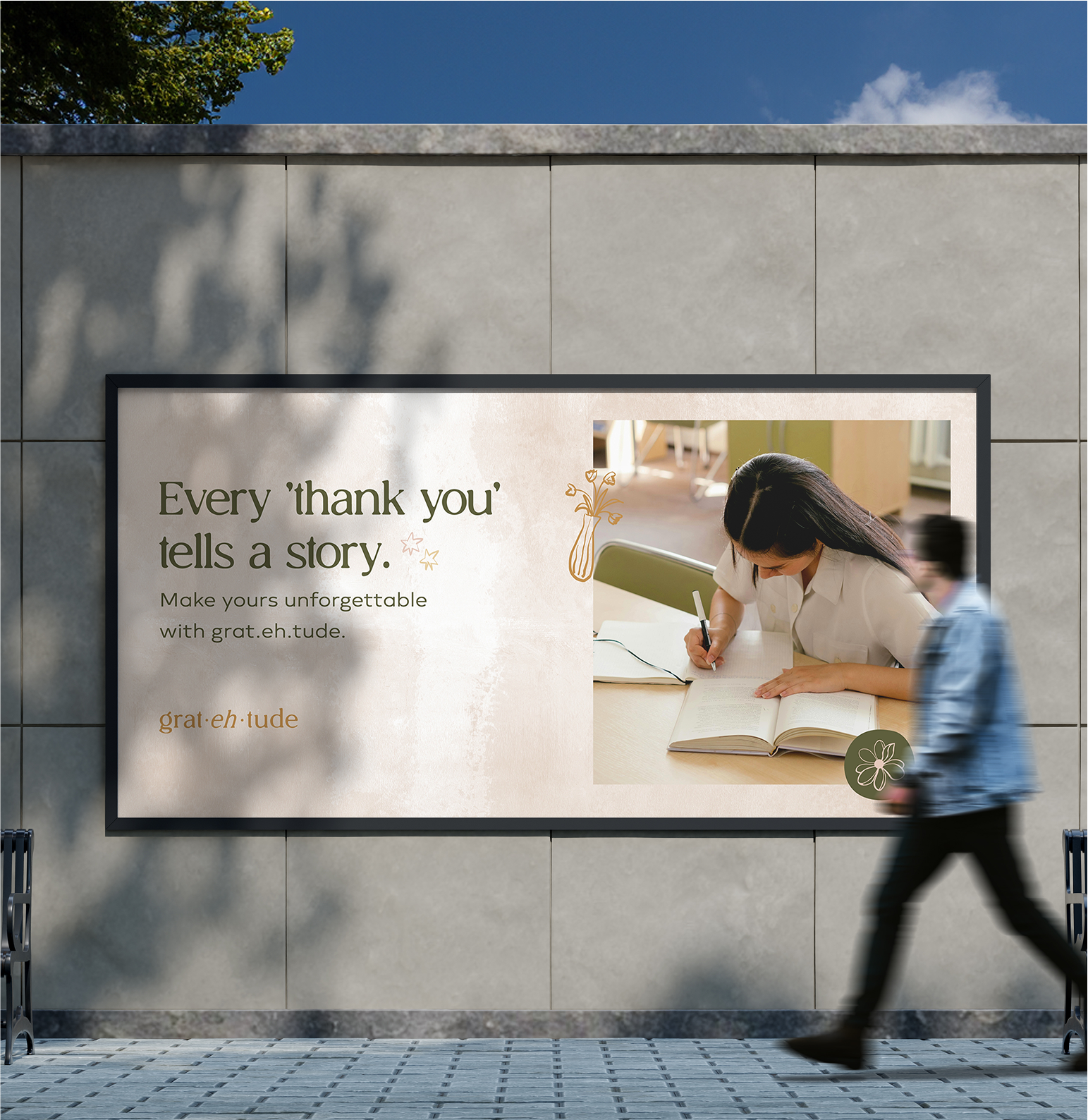 Outdoor advertisement with text 'Every 'thank you' tells a story. Make yours unforgettable with grat·eh·tude.' Features image of a person writing and blurred passerby.