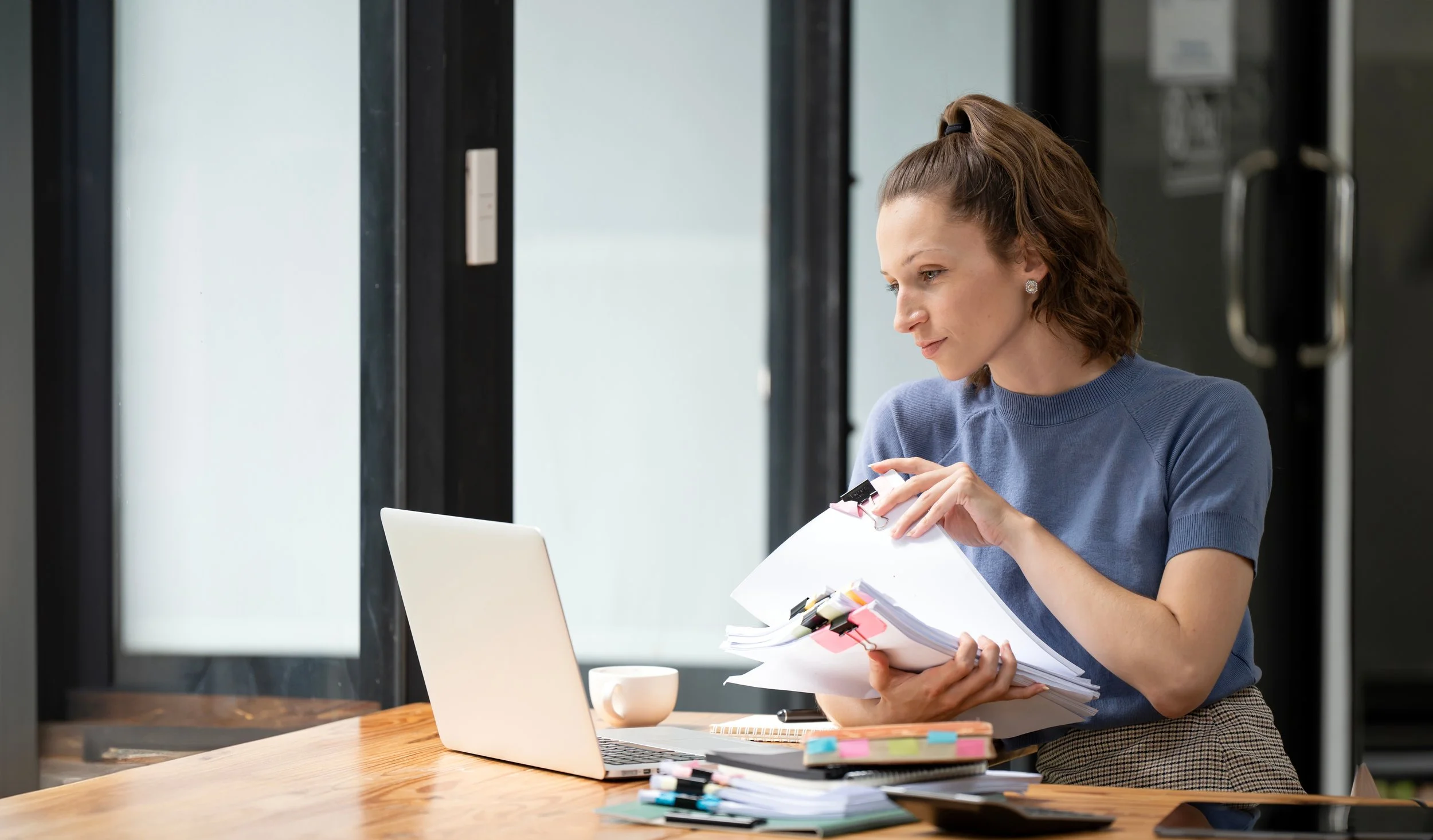 Scenic view of a mountain range with peaks partly covered by clouds, a lake in the foreground, and green hills on either side.