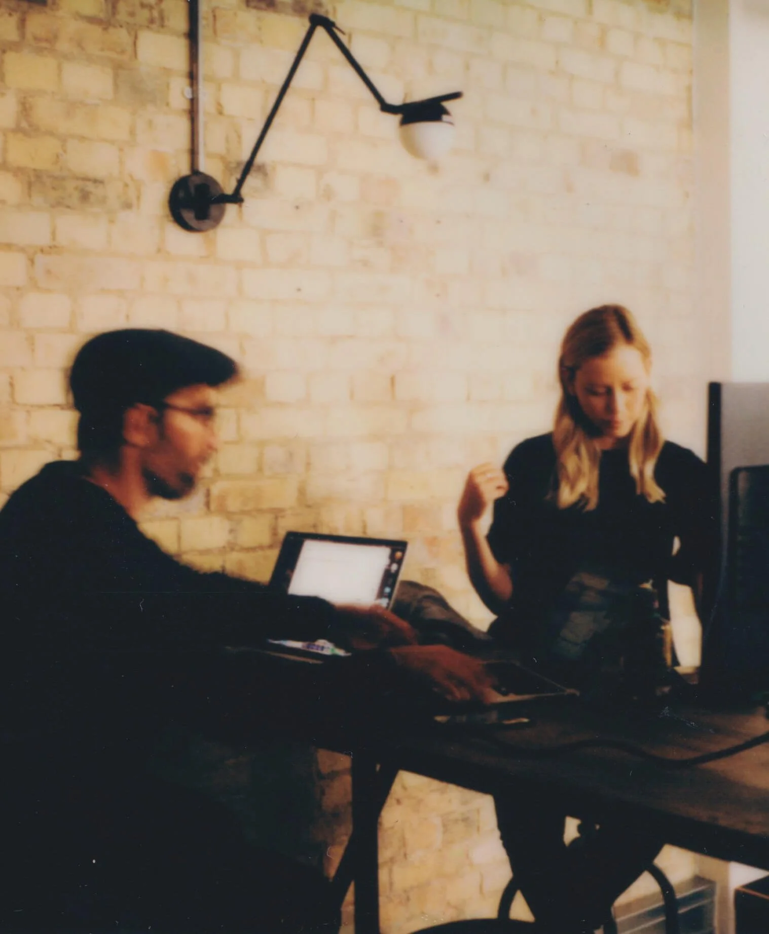 Shot of a man editing at a desk on a laptop with a colleague sitting across from him.