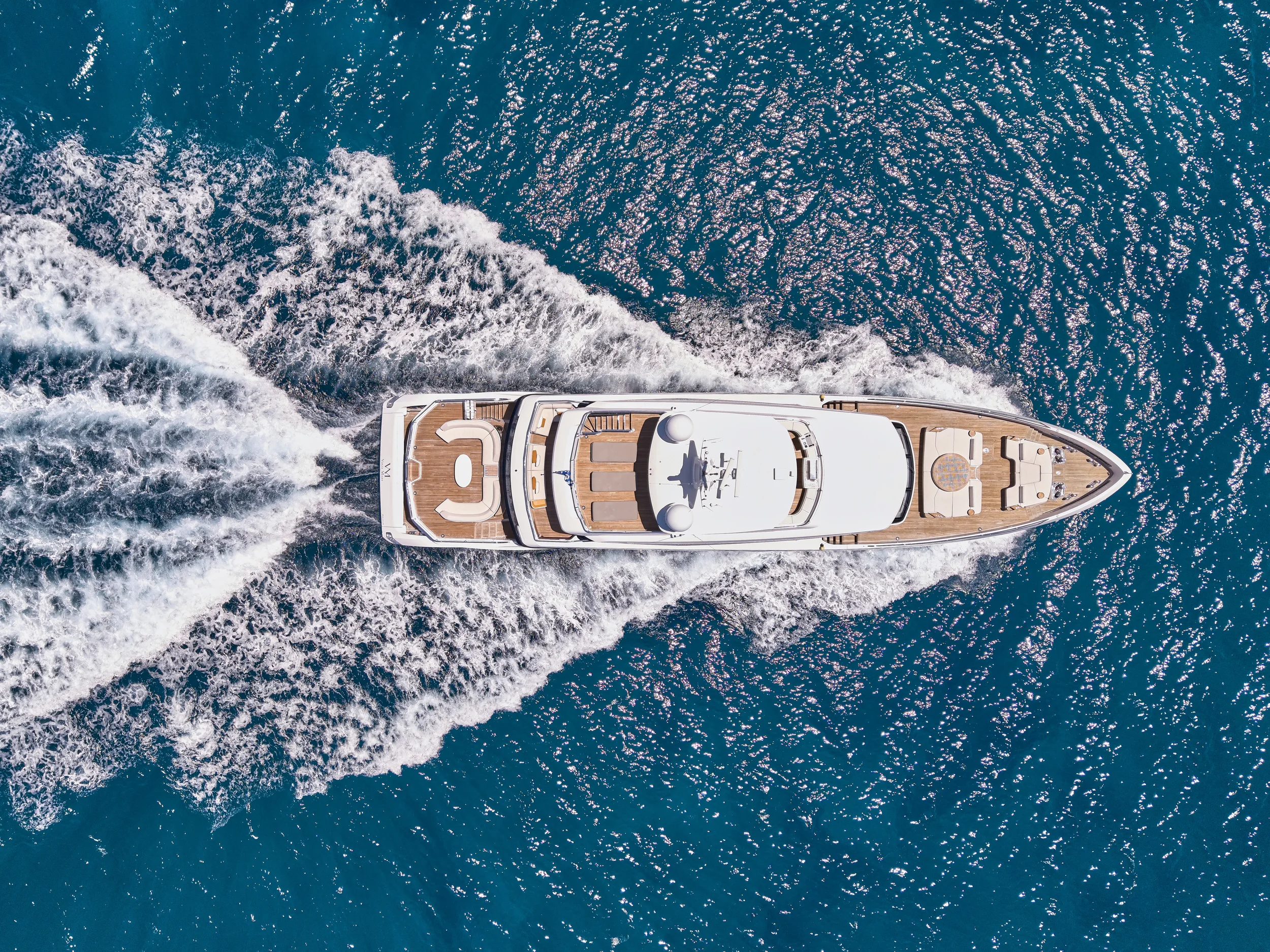 Aerial view of a luxury yacht moving through deep blue ocean waters