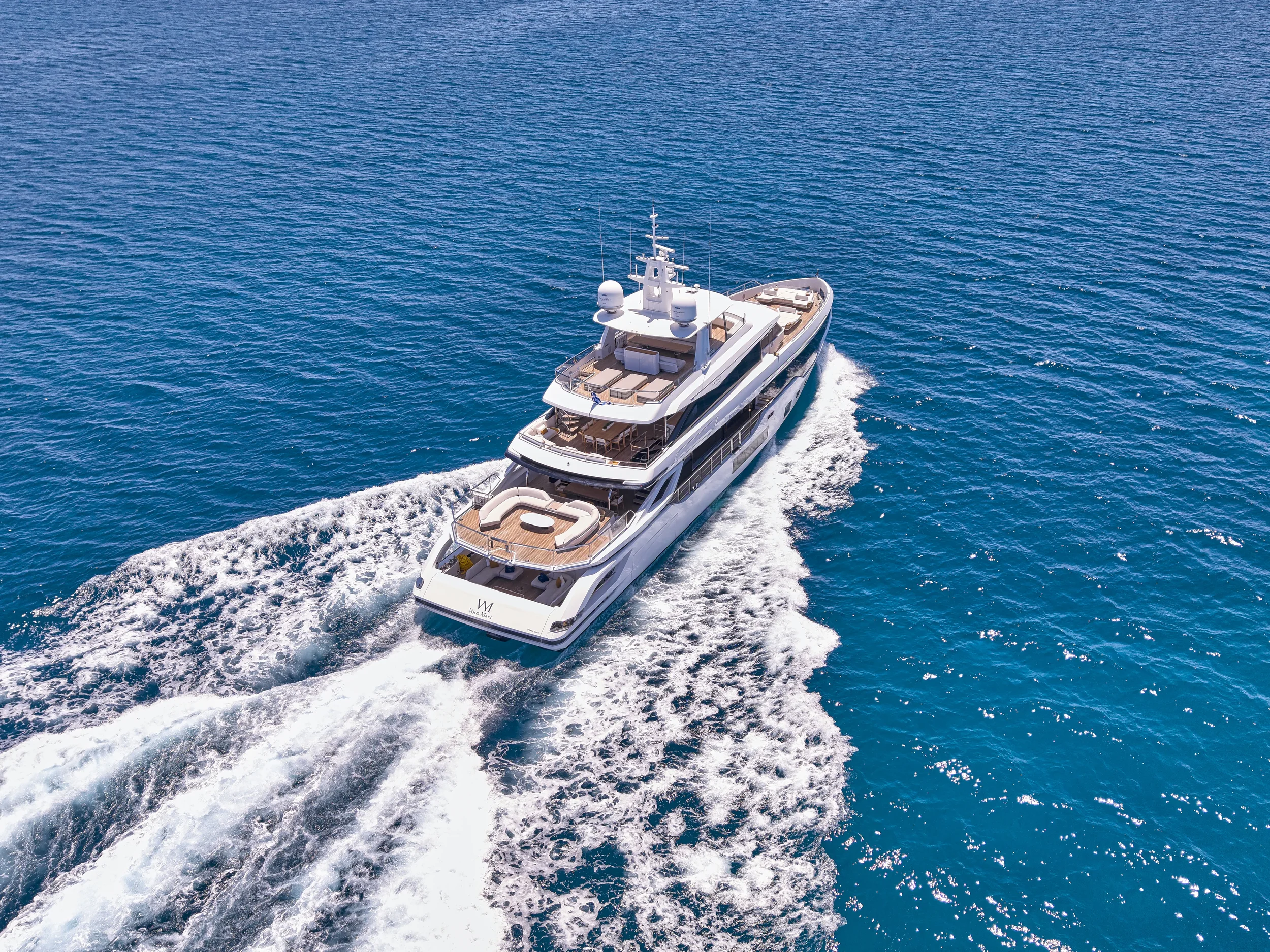 A luxury yacht cruising on the open ocean, creating a wake behind it.