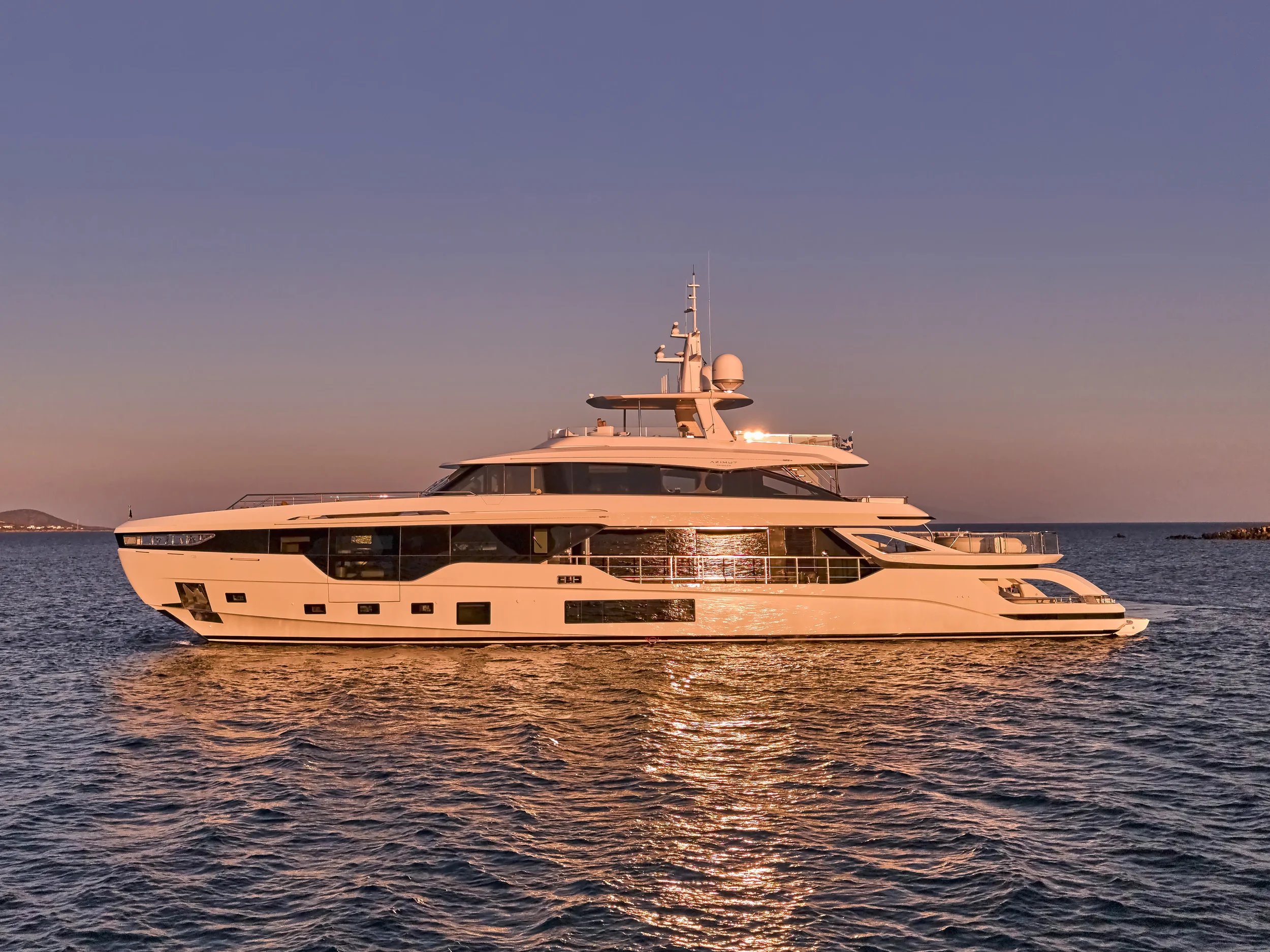 A luxury white yacht sailing on calm water during sunset.