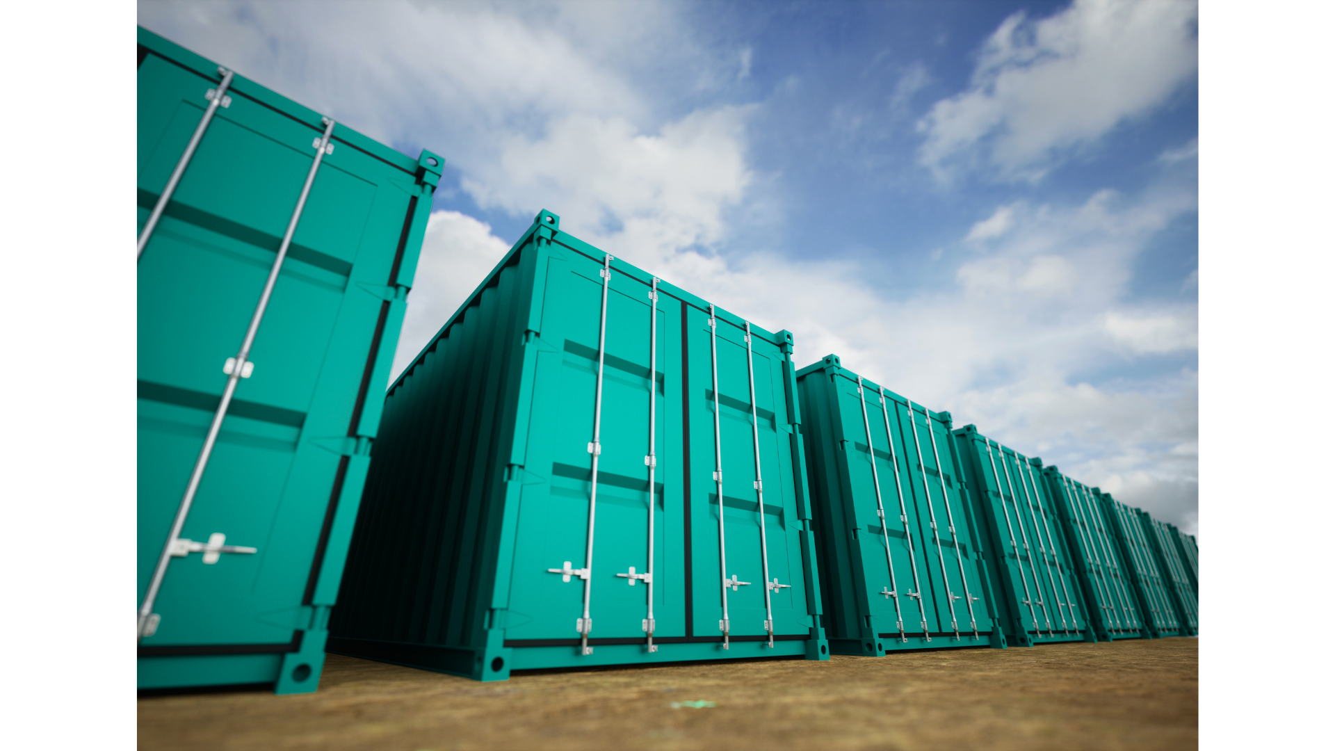 Row of teal shipping containers stacked outdoors under a partly cloudy sky.