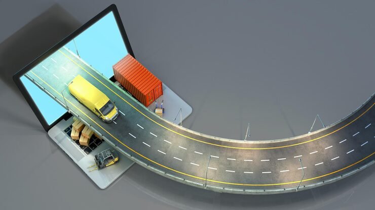Computer monitor with miniature road scene including a yellow delivery truck, an orange shipping container, and a forklift on a gray surface.