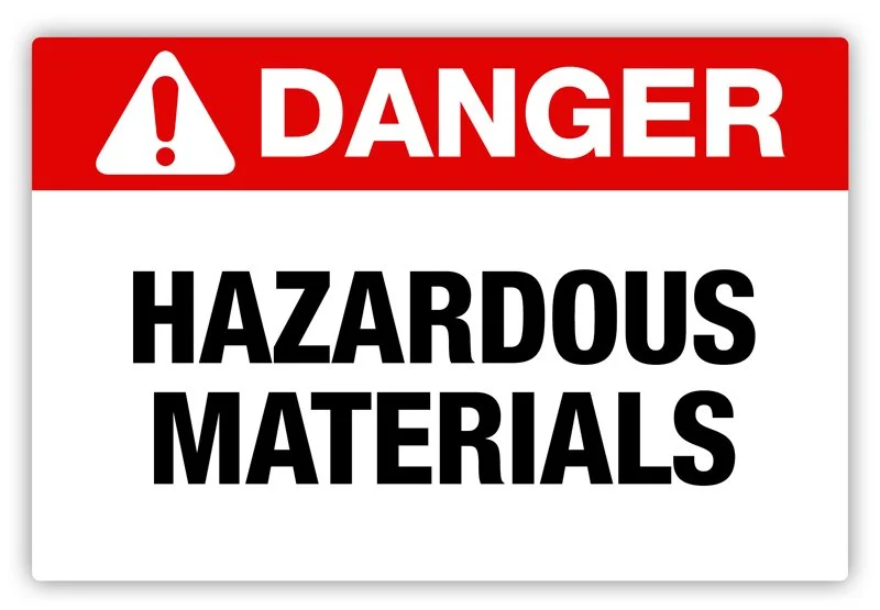 Warning sign with red section at the top containing a white exclamation mark and the word "DANGER"; white background with black text reading "HAZARDOUS MATERIALS".