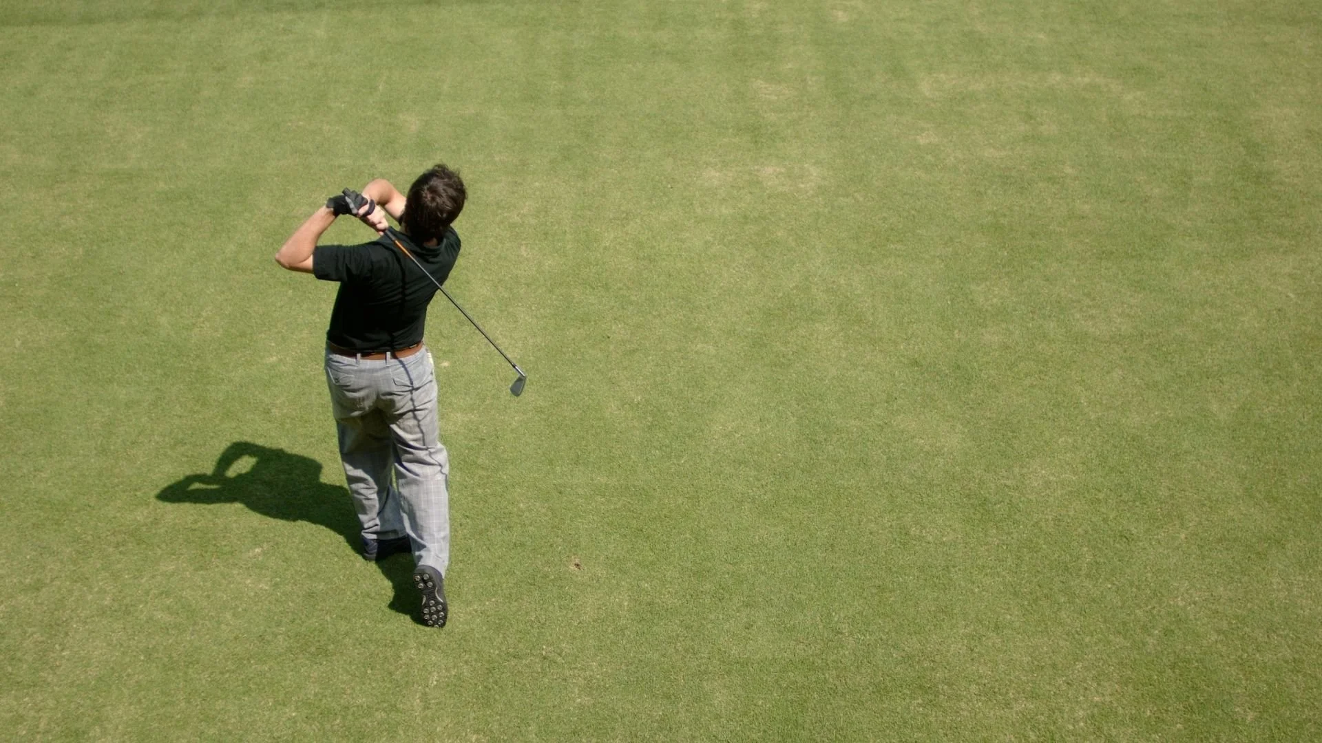 A man playing golf on a lush green golf course, preparing to hit the ball with a golf club.