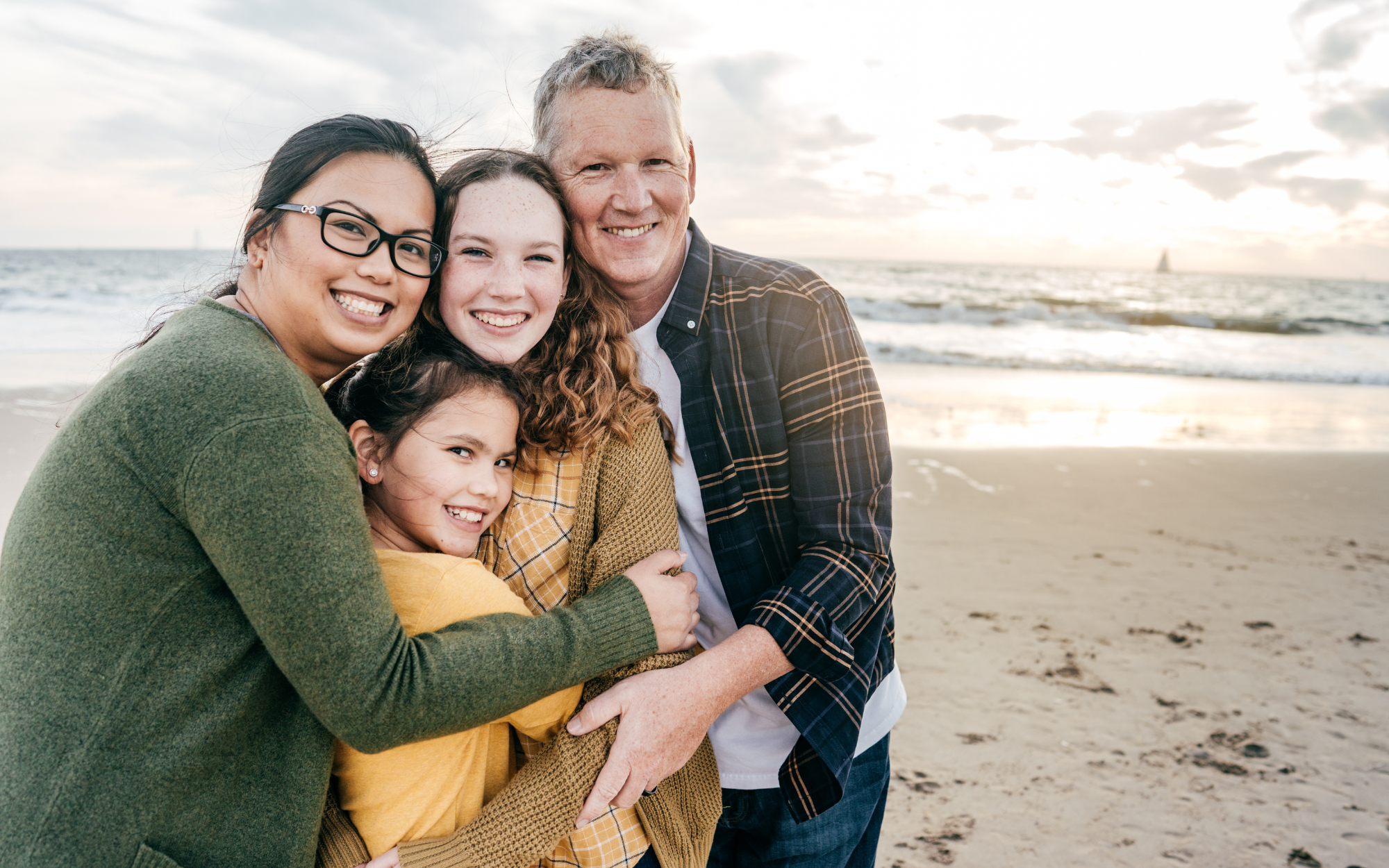 Family hugging and smiling on beach