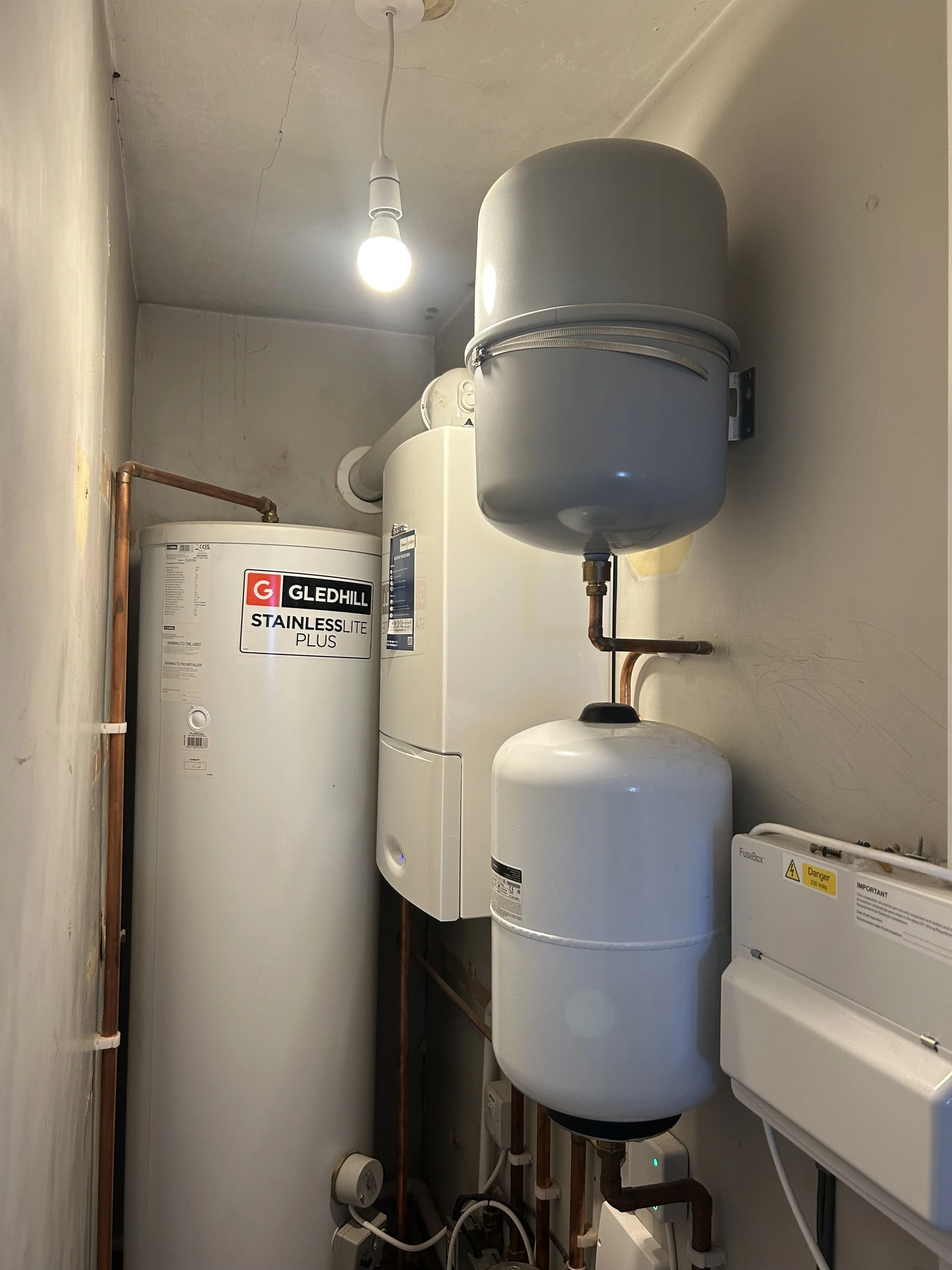 A utility room with a water heater, expansion tank, and electrical box.