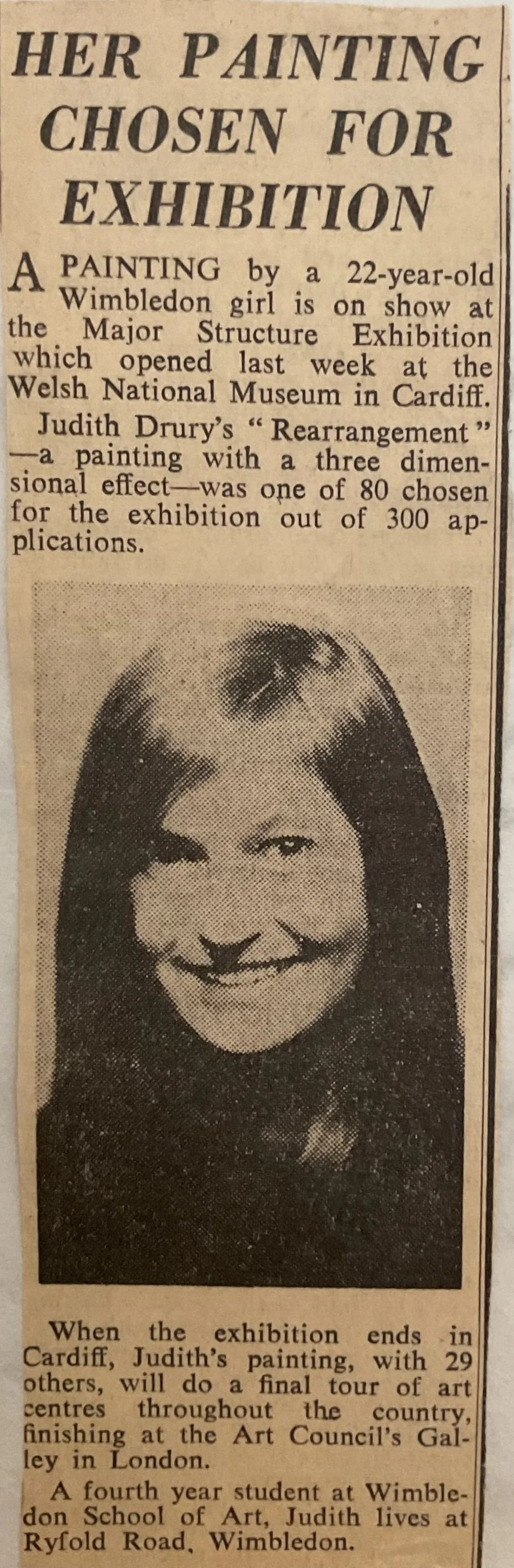 A newspaper clipping about a 22-year-old Wimbledon girl, Judith Drury, and her painting that was chosen for a major exhibition. The photo shows Judith Drury with a smiling expression and a distinctive hairstyle.