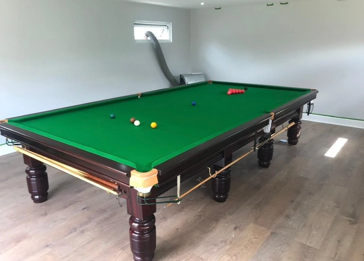 Pool table in a game room with some balls on the green felt surface.