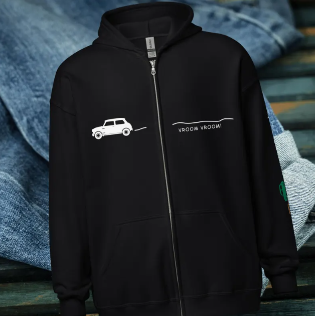 Black zip-up hoodie with a white drawing of a car and the words "VROOM VROOM!" on the front. Background includes blue denim fabric.
