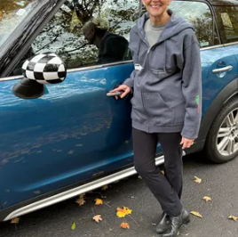 Woman standing next to a blue car with a checkered black and white side mirror
