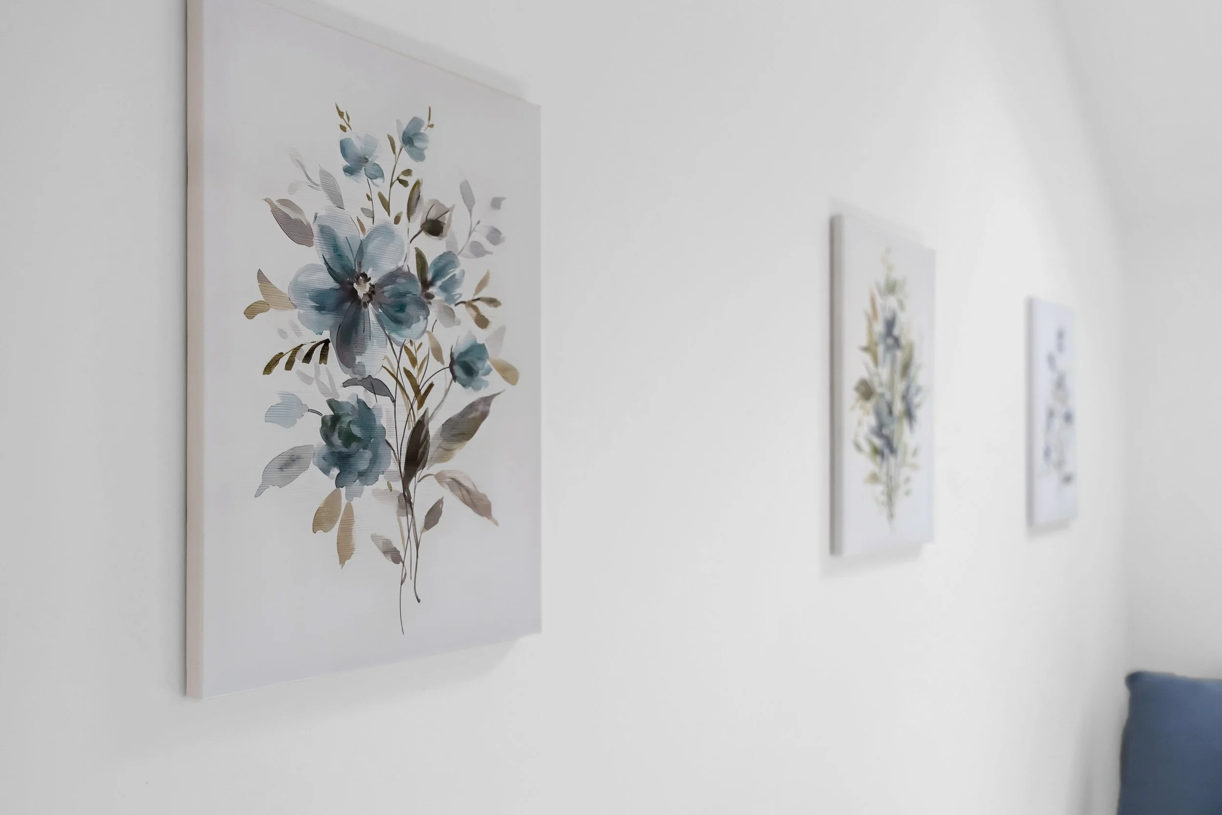 Wall with three watercolor floral art prints in white frames displayed on a white wall.