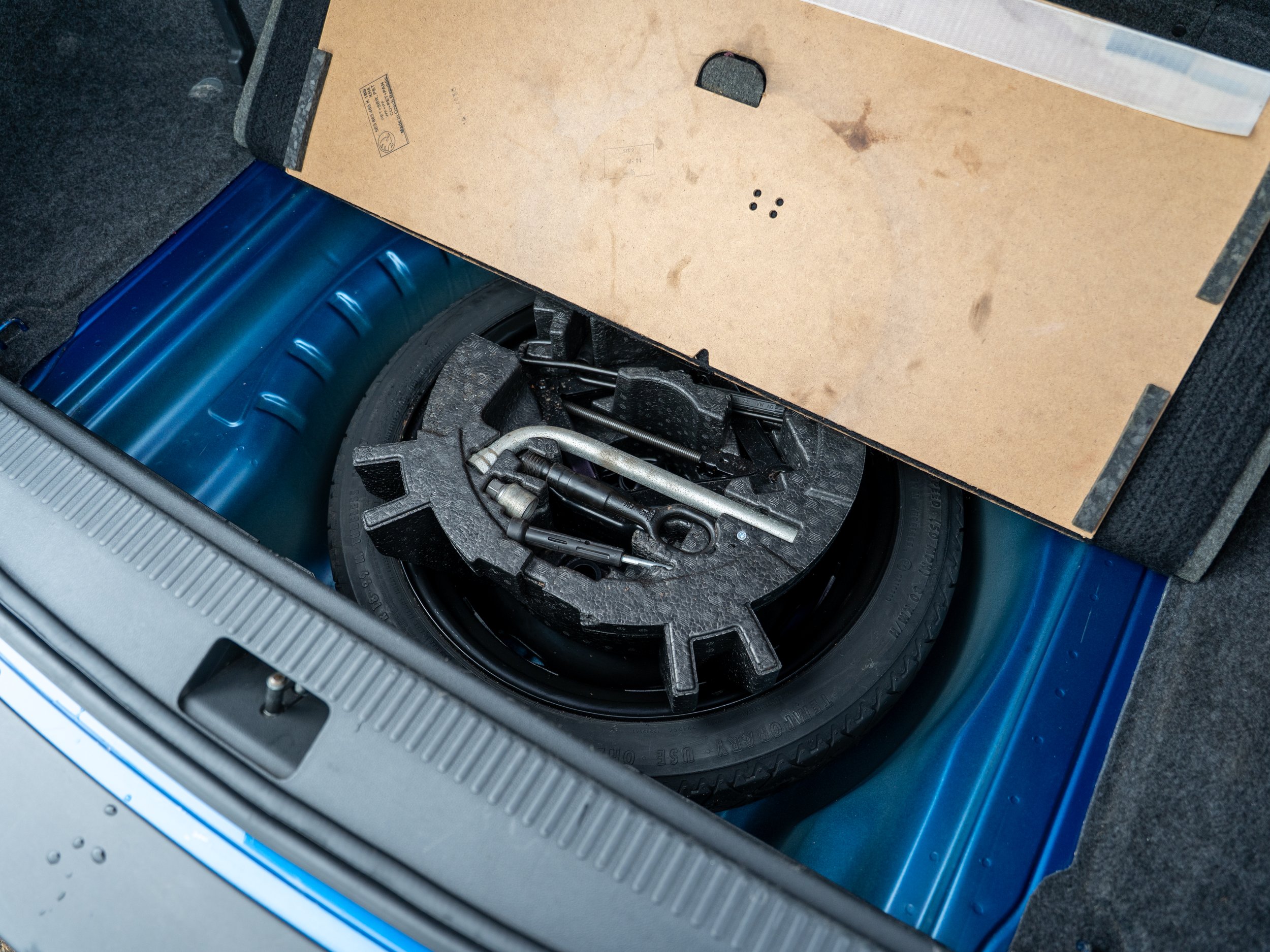 Spare tire with a foam toolbox and car tools in the trunk of a vehicle.